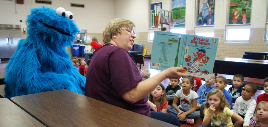 Nina Parker, Sheppard Elementary School teacher, and the Cookie Monster read a book to students during a visit to the school by characters from "Sesame Street Live" Dec. 4, 2012.  Both Elmo and the Cookie Monster met the students and participated in story time. (U.S. Air Force photo/Dan Hawkins)