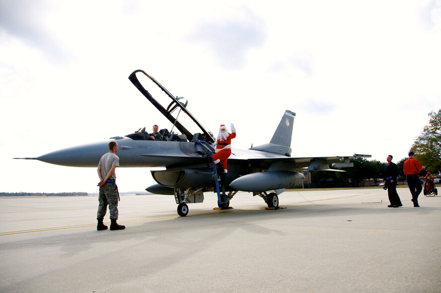 U.S. Air Force Lt. Col. Jared Hutchinson, 55th Fighter Squadron director of operations, sits in a F-16 Fighting Falcon while Santa waves to the children of Shaw at the 20th Operations Group Christmas Party, Shaw Air Force Base, S.C. Dec. 1, 2012. (U.S. Air Force photo by Capt. Ann Blodzinski/ Released)