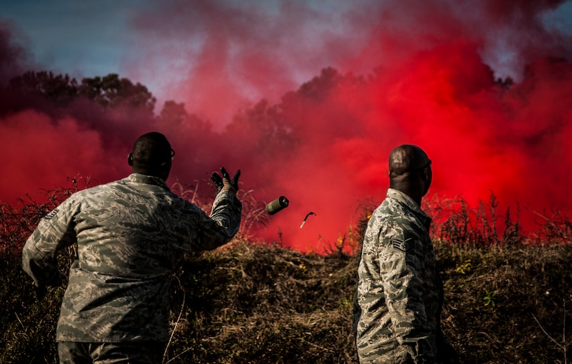 Tech. Sgt. Rudolph Stuart (left), 628th Security Forces Squadron noncommissioned officer in charge, throws a smoke grenade during Combat Readiness Training with the 628th Explosive Ordnance Squadron while Staff Sgt. Brandon Washington observes Nov. 30, 2012, at Joint Base Charleston – Air Base, S.C. Airmen attended an hour-long class to review safety procedures when handling grenades.  (U.S. Air Force photo/ Senior Airman Dennis Sloan)