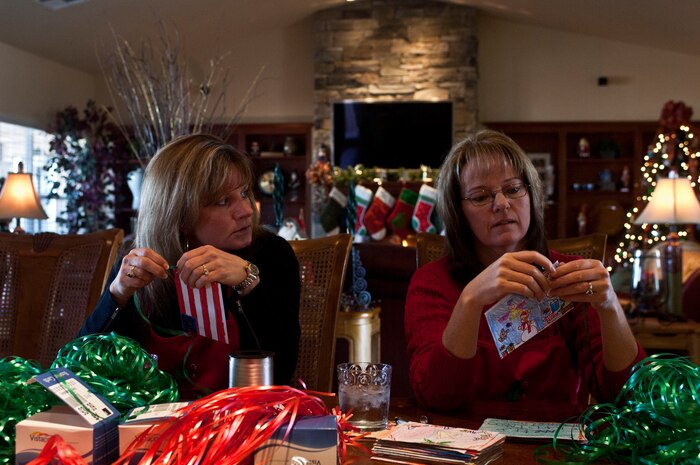 Terrie Hecker, wife of U.S. Air Force Col. James Hecker, 432d Wing commander, and Shannon Grynkewich, wife of Col. Alex Grynkewich, 57th Wing vice commander, tie ribbons to Christmas cards made by children from local schools during the 2012 Holiday Cookie Drive Dec. 03, 2012, at Nellis Air Force Base, Nev. The Holiday Cookie Drive is a tradition where donated confectionary delicacies are gifted to single Airmen living in the dormitories on Nellis and Creech Air Force Bases in an effort to bring the presence of family to Airmen during the holidays. (U.S. Air Force by Senior Airman Daniel Hughes)