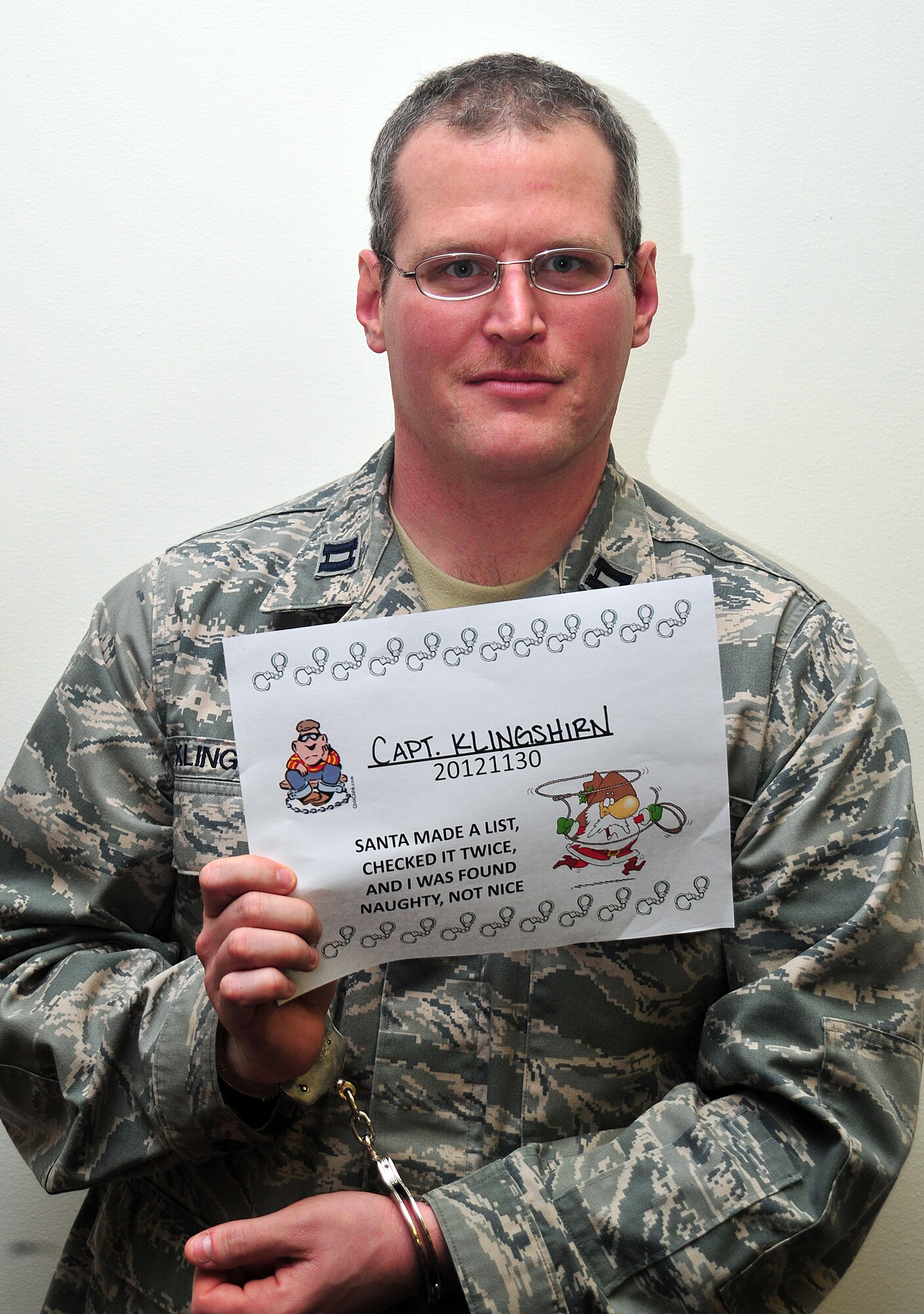 Capt. Michael Klingshirn poses for a simulated mug shot during the Operation Santa Lock-up fundraiser at Fairchild Air Force Base, Wash., Nov. 30, 2012. The event was to benefit Operation Warmheart and the Defenders Association. Members of Fairchild called in to put out an “arrest warrant” on their fellow wingman to be put into a simulated jail. The amount of time spent in jail was determined by the amount of money donated to the fundraiser. Klingshirn is the public health officer from the 92nd Aerospace Medicine Squadron. (U.S. Air Force photo by Airman 1st Class Taylor Curry)
