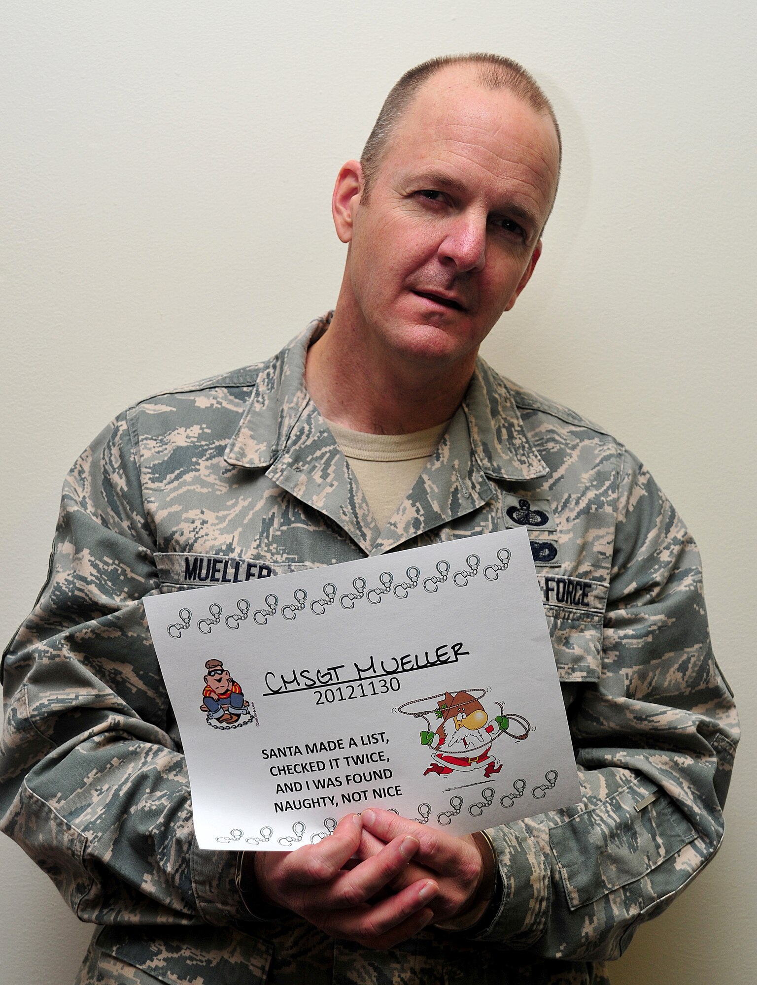 Chief Master Sgt. Robert Mueller poses for a simulated mug shot during the Operation Santa Lock-up fundraiser at Fairchild Air Force Base, Wash., Nov. 30, 2012. The event was to benefit Operation Warmheart and the Defenders Association. Members of Fairchild called in to put out an “arrest warrant” on their fellow wingman to be put into a simulated jail. The amount of time spent in jail was determined by the amount of money donated to the fundraiser. Mueller is the 92nd Mission Support Group superintendent.  (U.S. Air Force photo by Airman 1st Class Taylor Curry)