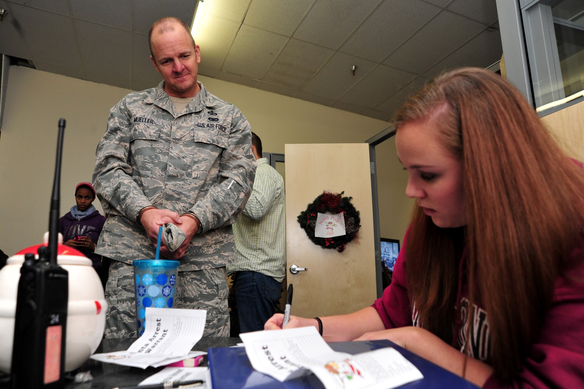 Chief Master Sgt. Robert Mueller gets “booked” during the Operation Santa Lock-up fundraiser at Fairchild Air Force Base, Wash., Nov. 30, 2012. The event was to benefit Operation Warmheart and the Defenders Association. Members of Fairchild called in to put out an “arrest warrant” on their fellow wingman to be put into a simulated jail. The amount of time spent in jail was determined by the amount of money donated to the fundraiser. Mueller is the 92nd Mission Support Group superintendent.  (U.S. Air Force photo by Airman 1st Class Taylor Curry)