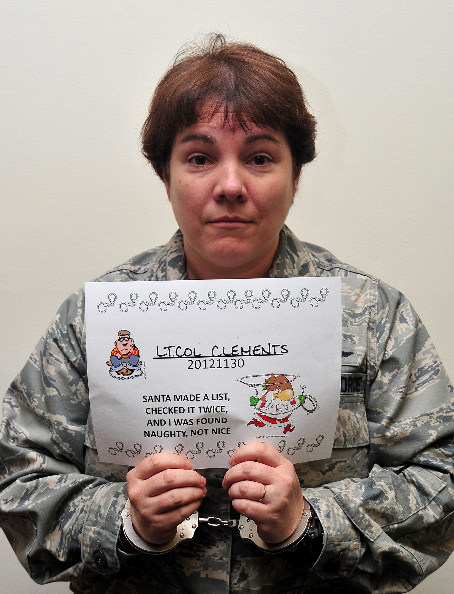 Lt. Col. Stacy Clements poses for a simulated mug shot during the Operation Santa Lock-up fundraiser at Fairchild Air Force Base, Wash., Nov. 30, 2012. The event was to benefit Operation Warmheart and the Defenders Association. Members of Fairchild called in to put out an “arrest warrant” on their fellow wingman to be put into a simulated jail. The amount of time spent in jail was determined by the amount of money donated to the fundraiser. Clements is the 92nd Mission Support Group deputy commander.  (U.S. Air Force photo by Airman 1st Class Taylor Curry)
