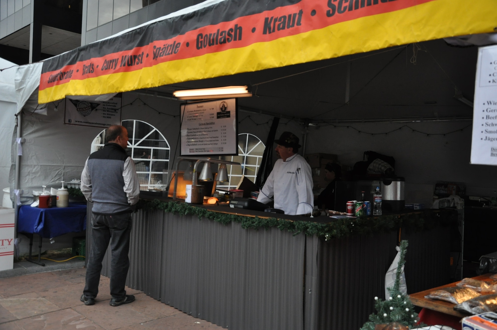 DENVER – A food vendor from Austria speaks with a potential customer at the 12th annual Denver Christkindl Market Nov. 28, 2012, in Skyline Park. Vendors from around the world gathered in the park to share their cultural traditions with people in the area. The market will continue through Dec. 22. (U.S. Air Force photo by Staff Sgt. Kali L. Gradishar)