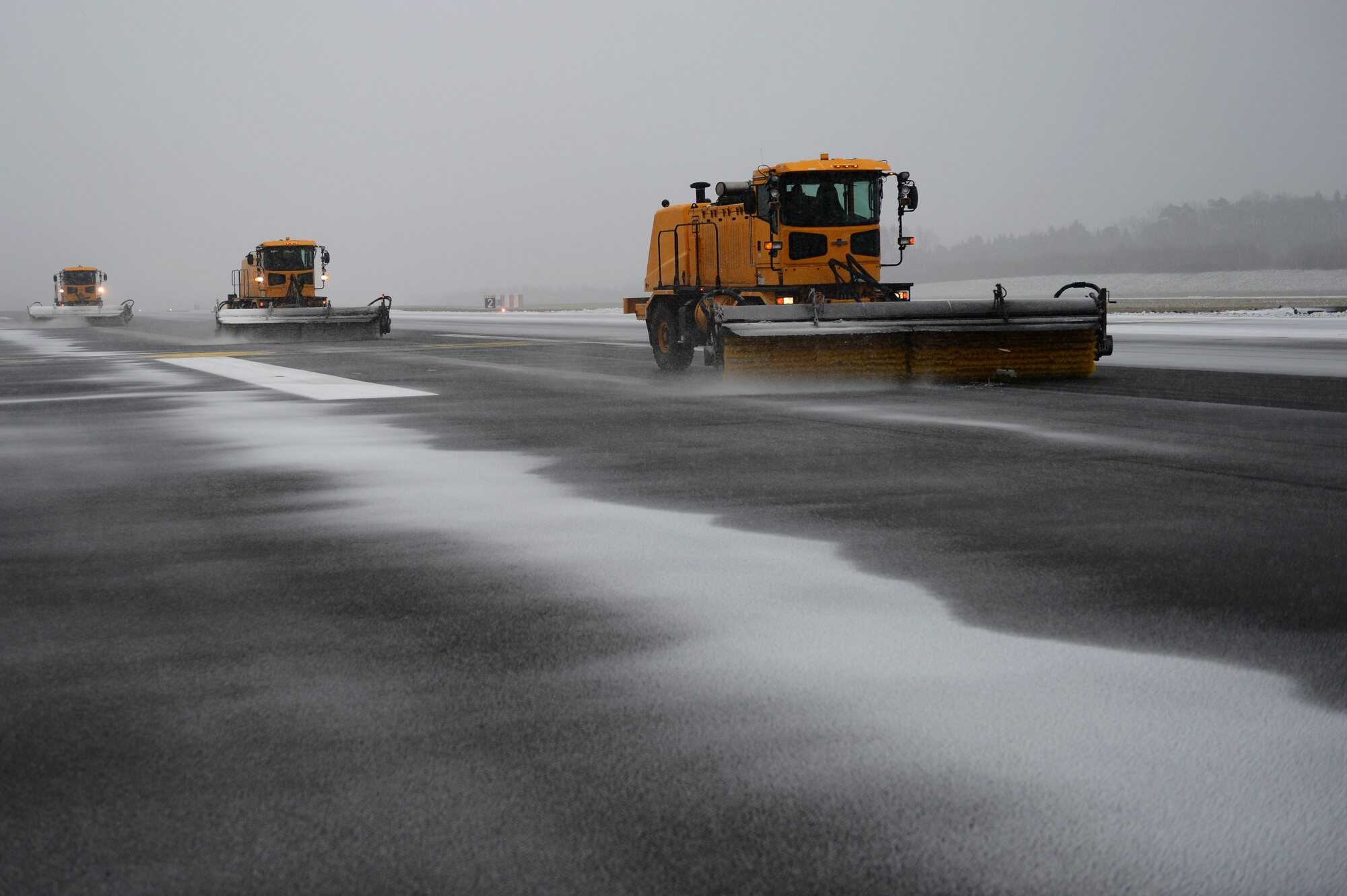 SPANGDAHLEM AIR BASE, Germany – Members of the 52nd Civil Engineer Squadron snow patrol clear the flight line using vehicles such as a snow broom truck after the first snow of the season. The 52nd CES pavement maintenance and heavy equipment shop augments more than 30 Airmen each year to ensure Spangdahlem personnel continue to meet mission requirements. (U.S. Air Force photo by Airman 1st Class Dillon Davis/Released)