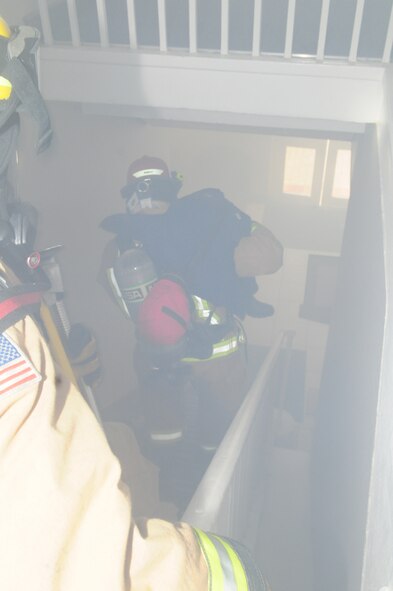 Staff Sgt. David Ordway, right, 100th Civil Engineer Squadron Fire Department firefighter, moves carefully down a smoke-filled stairway inside building 438 Dec. 3, 2012, at RAF Mildenhall, England. The 100th Security Forces Squadron building was filled with smoke, and firefighters responded and rescued three casualties as part of an operational readiness exercise. The ORE is one of many exercises in preparation for the combined unit inspection in 2013. Inspector General augmentees  and IG inspectors observed the exercise and will provide base leadership a graded perspective on RAF Mildenhall’s ability to perform its mission both at home station and at deployed locations. (U.S. Air Force photo by Karen Abeyasekere/Released)