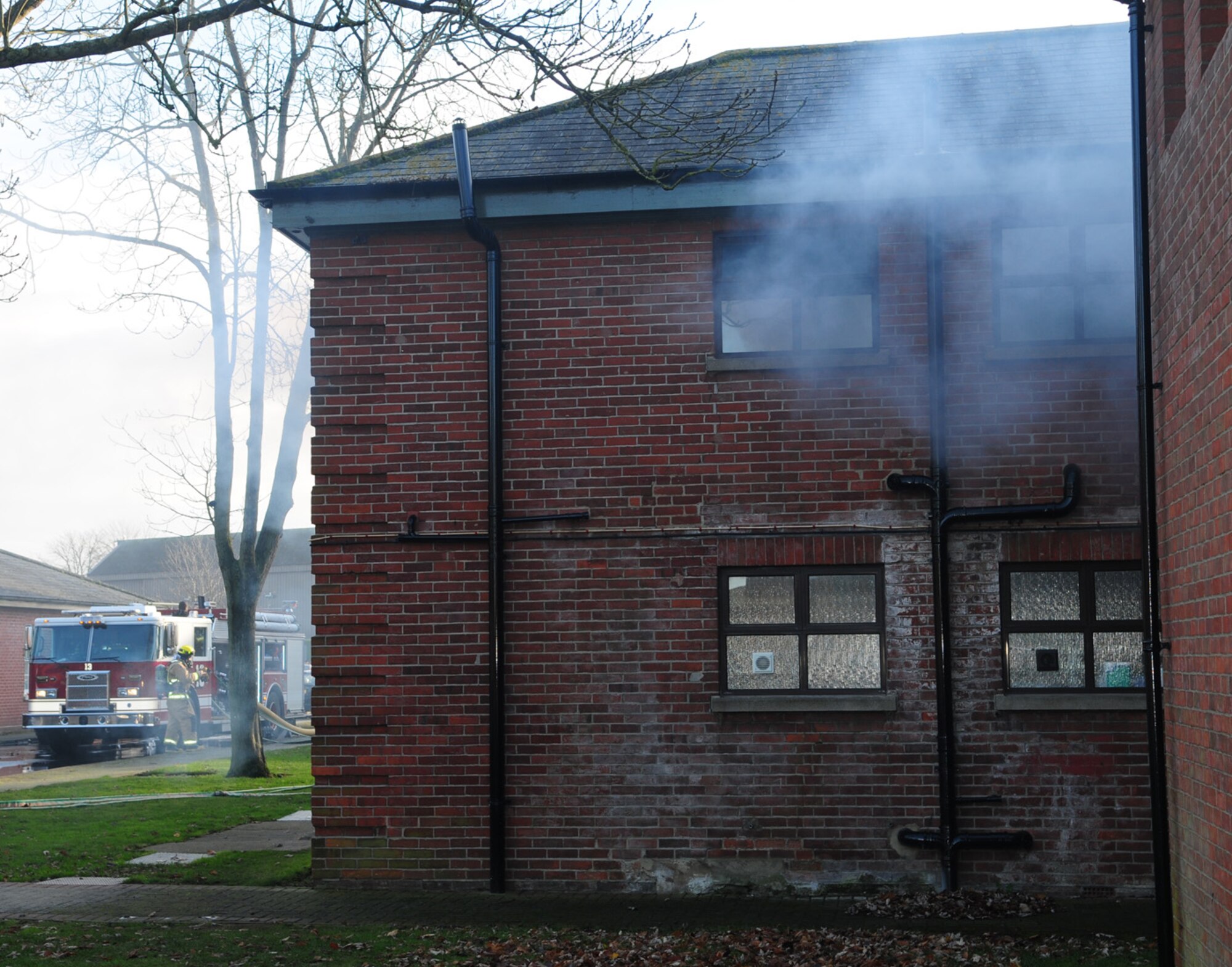 Smoke pours out of the window of building 438 Dec. 3, 2012, at RAF Mildenhall, England, during an operational readiness exercise to test the base’s response capabilities. Firefighters responded to the smoke-filled 100th Security Forces Squadron building as people inside evacuated. The scenario involved three missing people– two adults and one child. The responders went inside to fight the fire and rescue the simulated casualties, which they did successfully. The ORE is one of many exercises in preparation for a combined unit inspection in 2013. Inspector General augmentees and IG inspectors observed the exercise and will provide base leadership a graded perspective on RAF Mildenhall’s ability to perform its mission both at home station and at deployed locations. (U.S. Air Force photo by Karen Abeyasekere/Released)