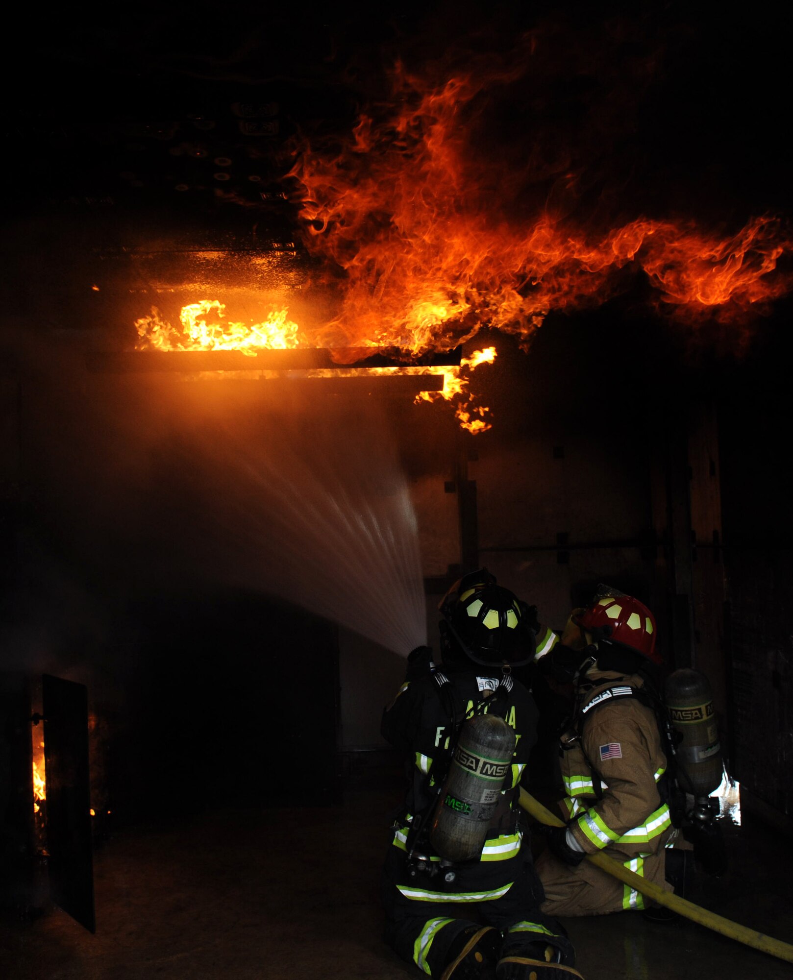 Kadena firefighters fight a simulated kitchen fire during a structural burning training exercise on Kadena Air Base, Japan, Nov. 29, 2012. A cabinet and stove were connected to propane tanks and a pilot light to start the fire during the exercise. The structure burning training is required for firefighters to complete annually. (U.S. Air Force photo/Airman 1st Class Hailey R. Davis)
