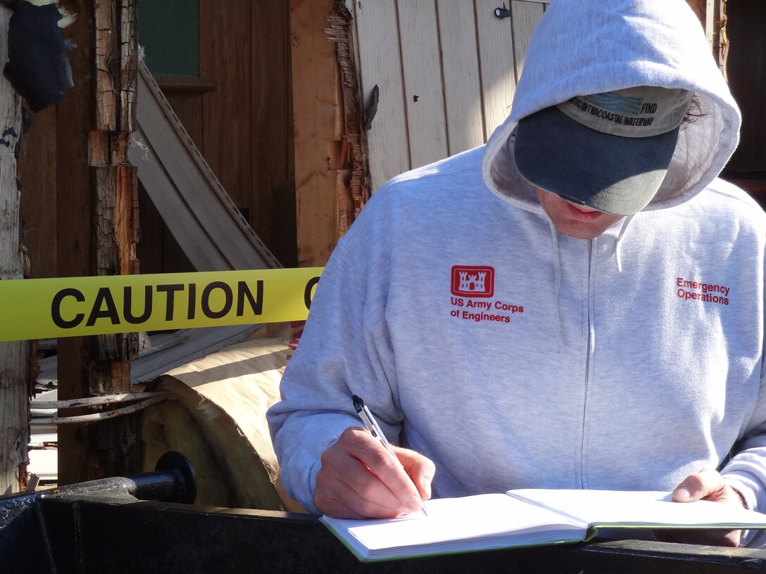 Paul DeMarco, national environmental policy act (NEPA) specialist, U.S. Army Corps of Engineers, takes notes at the Moonachie Aid and Rescue Squad building, Moonachie, N.J., to assess any environmental impacts for placing temporary facilities for the squad as their building was flooded and badly damaged from Hurricane Sandy. The U.S. Army Corps of Engineers mission assigned by FEMA in New Jersey is to assess fire, police, school, city halls, EMS, hospitals and public works facilities. The assessment of these facilities in New Jersey is complete for all 158 facilities and found a need for 29 temporary facilities. Those that require temporary structures are located throughout the state and include: eight fire stations, eight police stations, three schools, one city hall, one EMS and eight public works facilities. The Corps is also providing Technical Assistance which will provide site layouts to include the placement of structures, infrastructure, and other site requirements, and in this case critical public facilities team is completing 30% design for local entities (and assisting with the independent government estimate), and lastly assisting in the preparation of environmental documentation as required by local, state and the Federal government. (Photo by Andrew Stamer, U.S. Army Corps of Engineers)