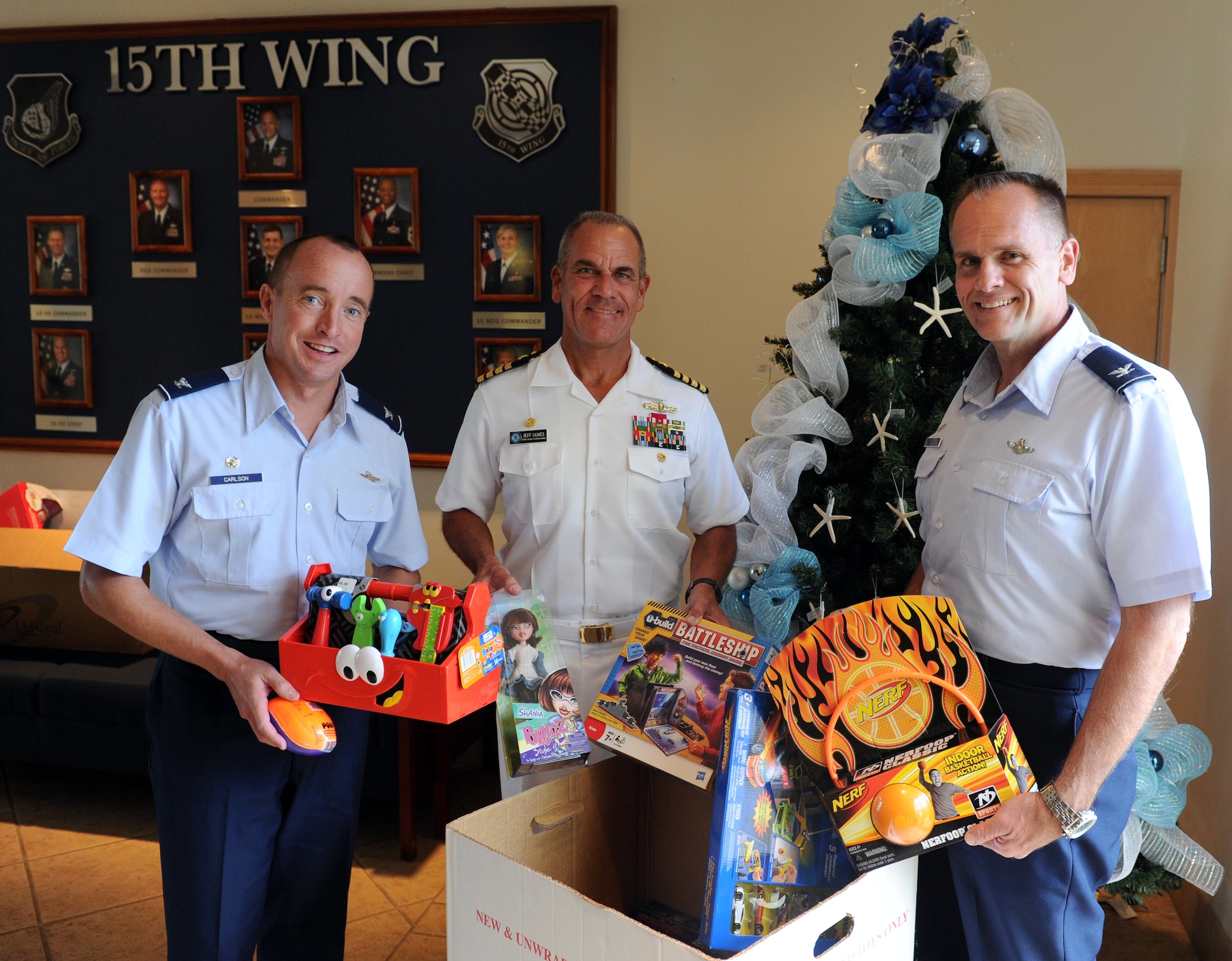 (From left) Col. Dann Carlson, 647th Air Base Group commander, Captain Jeff James, Joint Base Pearl Harbor-Hickam, Hawaii, commander, and Col. Johnny Roscoe, 15th Wing commander, donate toys Dec. 3 as a show of support for the annual Toys for Tots campaign. The campaign, which collects toys for less fortunate children in the local community, runs through Dec. 14. (U.S. Air Force photo by Staff Sgt. Nathan Allen)