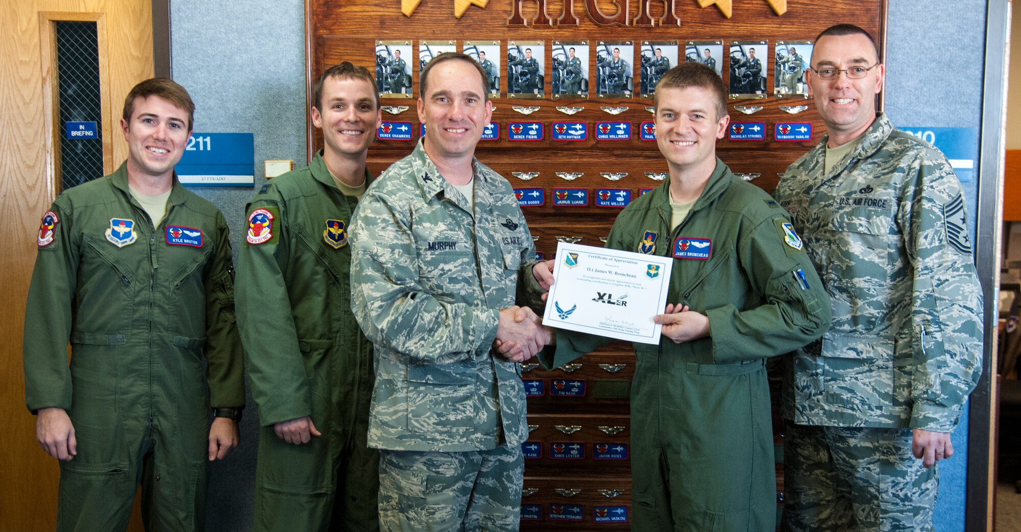 1st Lt. James Broncheau, 87th Flying Training Squadron assistant flight commander, poses with Col. Tom Murphy, 47th Flying Training Wing commander, and Chief Master Sgt. Garry Berry, 47th FTW command chief, after being presented the XLer of the week award at Laughlin Air Force Base, Texas, Nov. 14, 2012. The XLer is a weekly award chosen by wing leadership and given to those who consistently make outstanding contributions to Laughlin and their unit. (U.S. Air Force photo/Airman 1st Class Nathan Maysonet)
