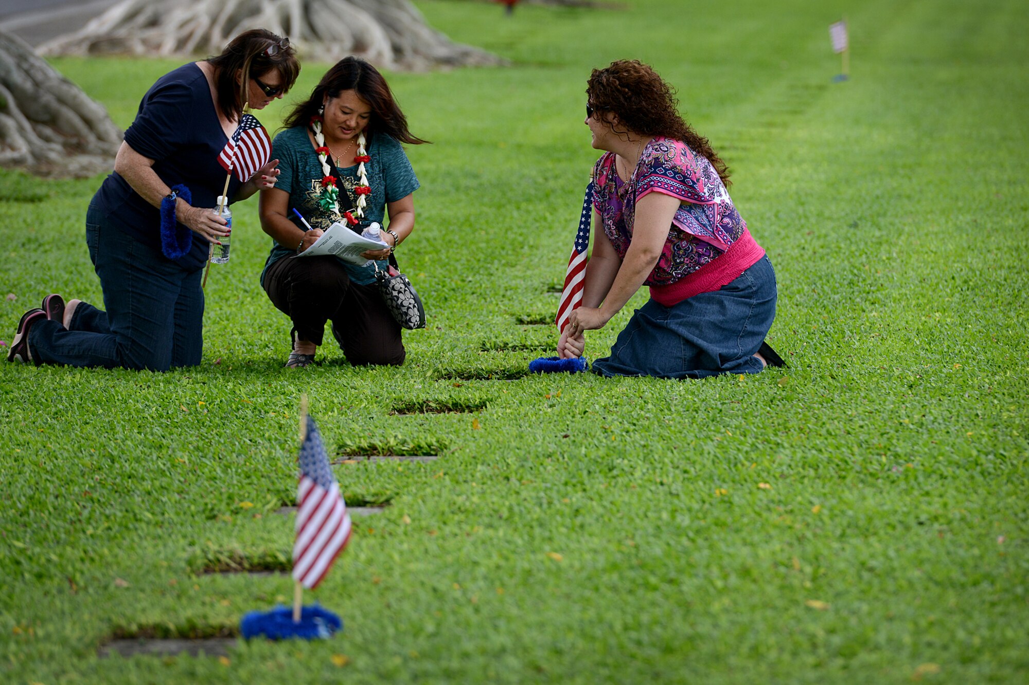 Laura McLeod, Jessie Higa and Stephanie Meares place an American flag and a lei at the headstone of a fallen Army Air Forces Airmen who was killed during the Dec. 7, 1941, attacks on Oahu at the National Cemetery of the Pacific, at Punchbowl in Honolulu, Dec. 2, 2012. Higa, a volunteer historian and president of the Hickam History Club, directed a team of volunteers to honor the men who were killed on that infamous day. Higa has studied WWII history, with an emphasis on Hickam Field for more than 8 years. (U.S. Air Force photo/Staff Sgt. Mike Meares)