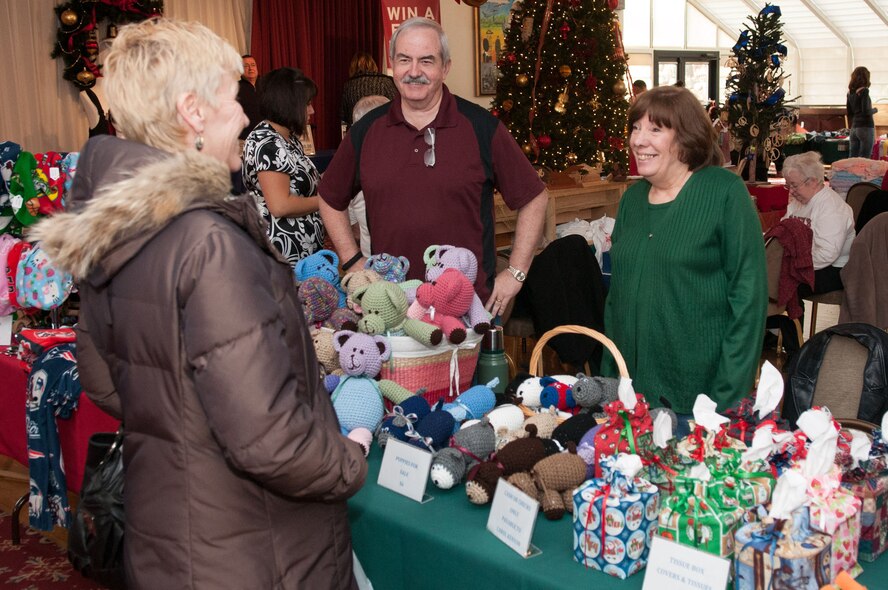 HANSCOM AIR FORCE BASE, Mass. – Judy Haberman (left) looks at some of the goods from Doug and Carol Kenyon’s table during the Holiday Bazaar at the Minuteman Commons Nov. 29. The Hanscom community was invited to the bazaar to shop from a selection of jewelry, ornaments, candles, hand knitted and crocheted gifts, gift bags, woodworking items and more from a wide variety of vendors. (U.S. Air Force photo by Rick Berry)