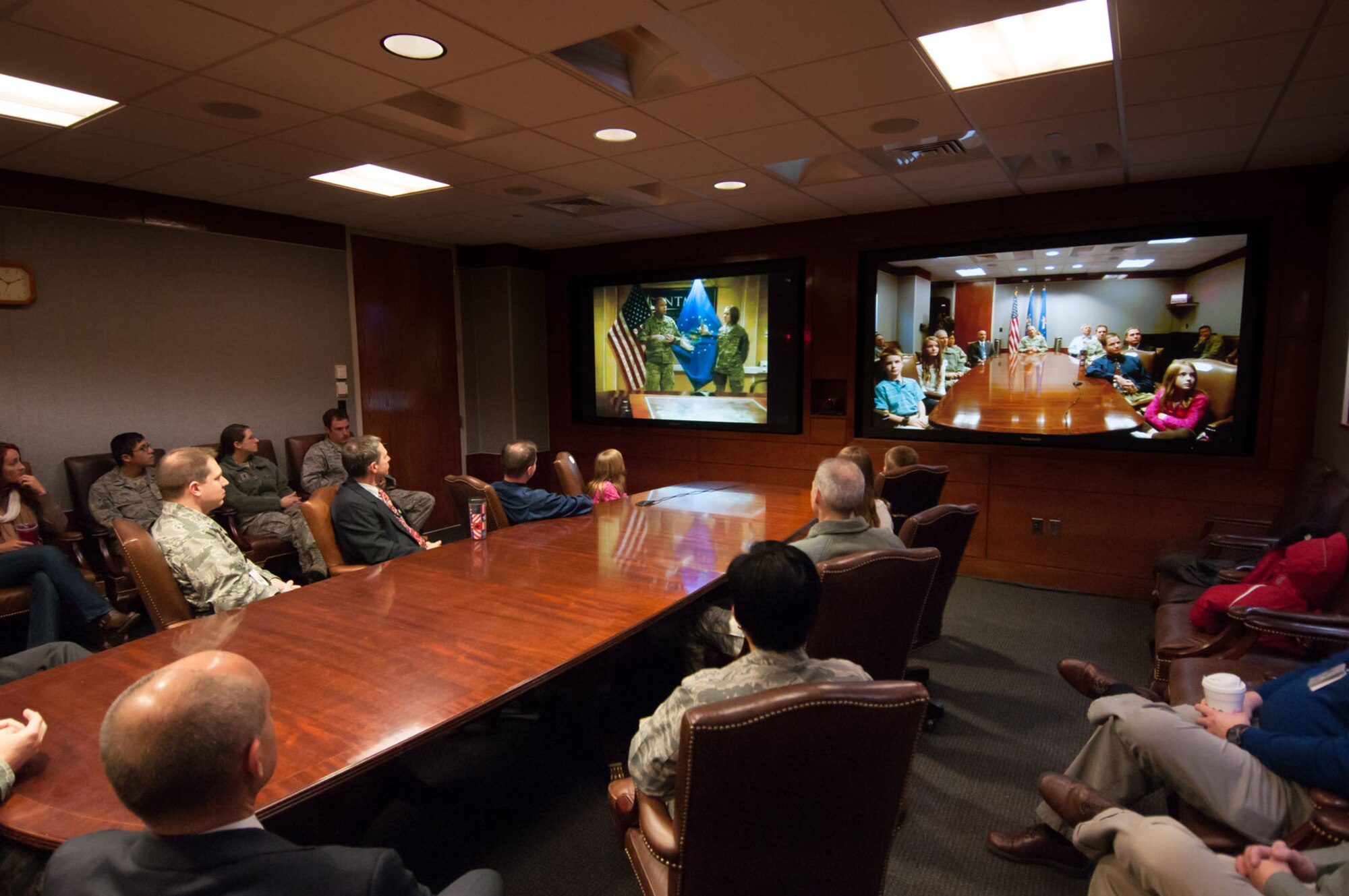 HANSCOM AIR FORCE BASE, Mass. - Family, friends and co-workers look on as Army Col. Matthew Schwab (left screen) discusses the accomplishments of newly promoted Lt. Col. Stephani Hunsinger via video teleconference Nov. 29. Lt. Col. Hunsinger, a member of the C3I&N Directorate, is deployed to Afghanistan along with other coalition partners. (U.S. Air Force photo by Rick Berry)