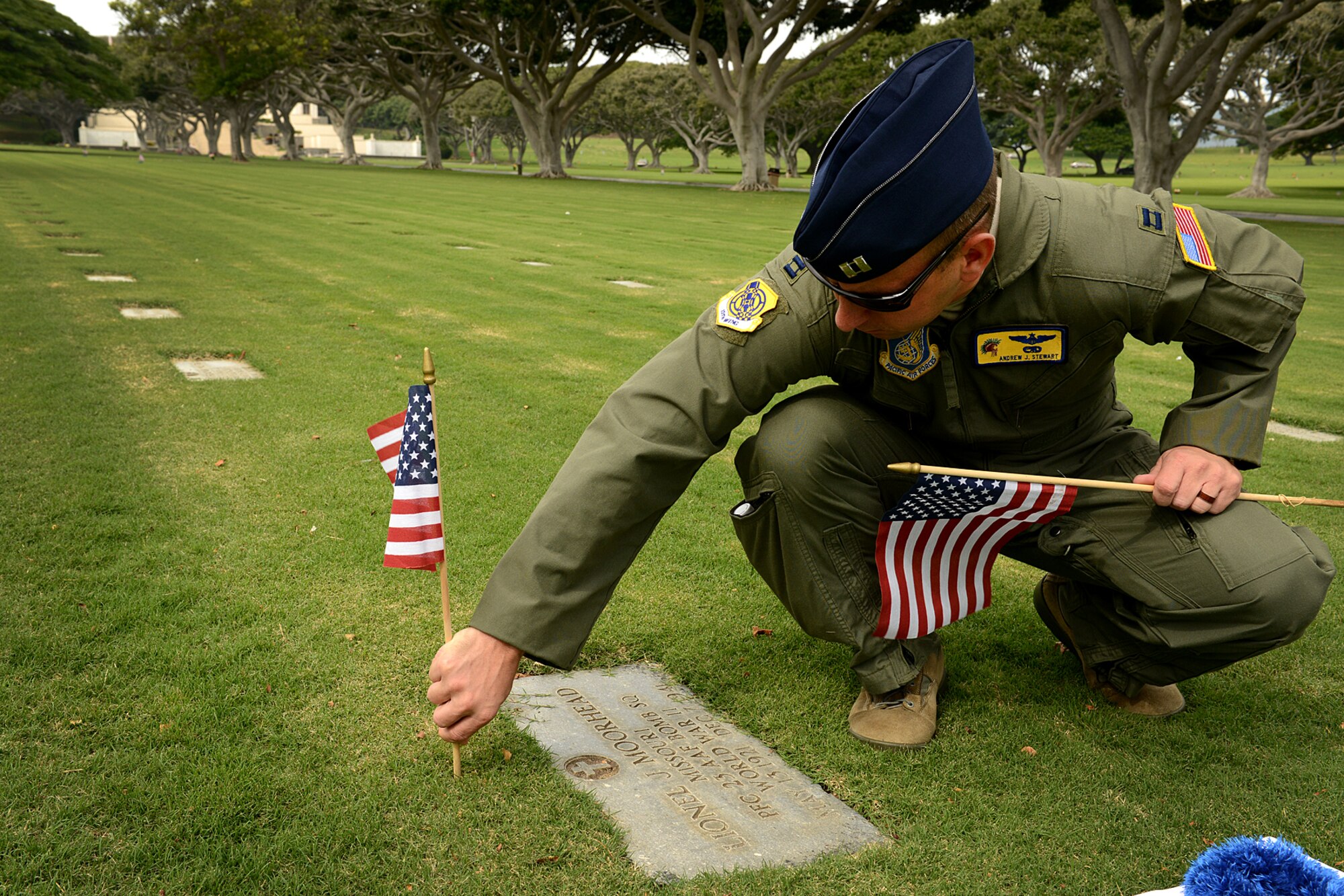 Capt. Andy Stewart, 15th Wing commander’s Action Group, places an American flag and handmade lei at the top of a gravesite, Dec. 2, 2012, at the National Cemetery of the Pacific, at Punchbowl in Honolulu. Stewart, and nine other volunteers placed 92 flags among the 34,000 gravesites on the grounds of the cemetery to honor the men who lost their lives at Hickam Field on Dec. 7, 1941. Stewart cleaned debris from each of the gravesites he placed a marker and saluted each Airman. (U.S. Air Force photo/Staff Sgt. Mike Meares)