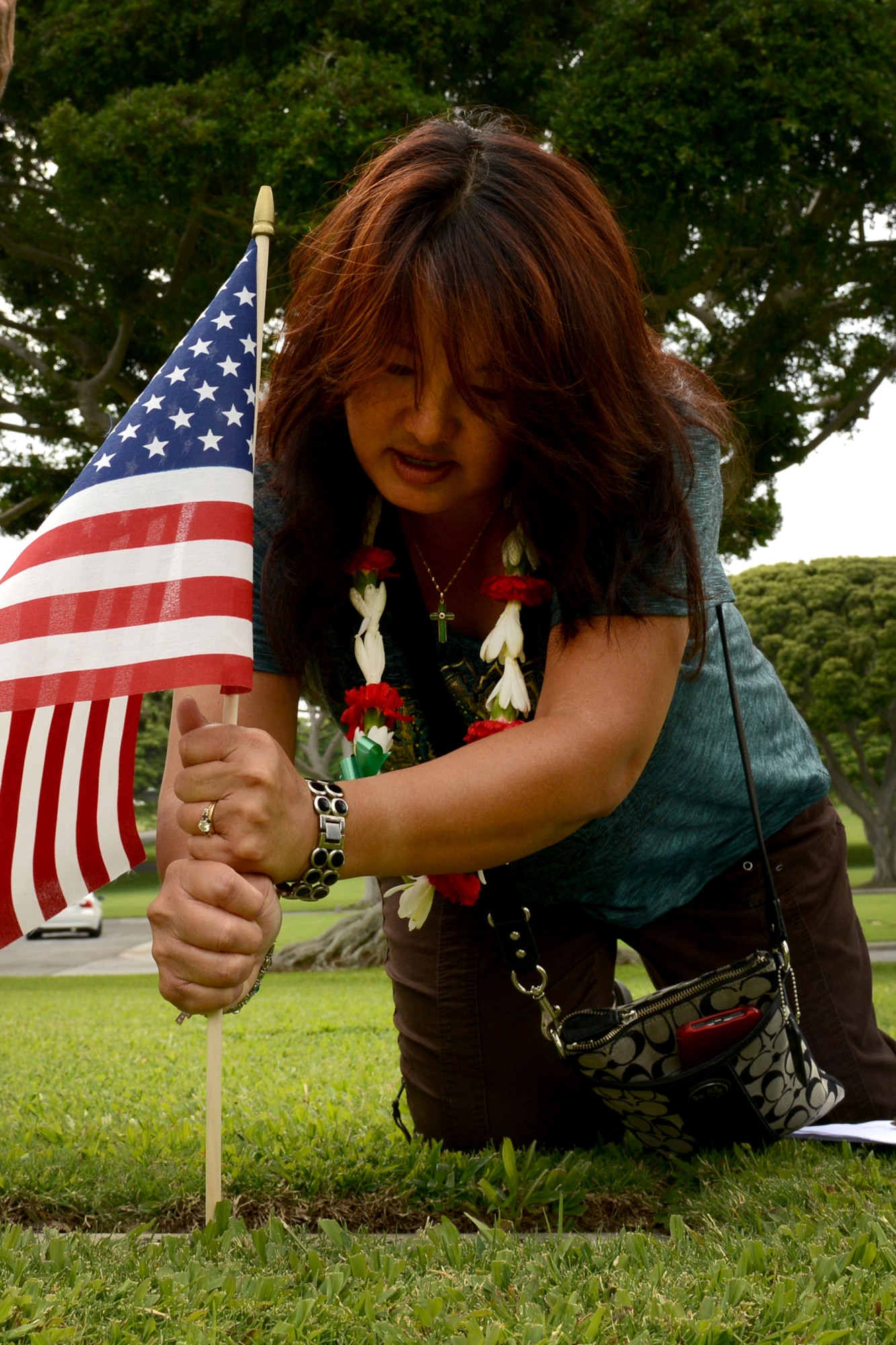 Jessie Higa, volunteer historian and president of the Hickam History Club, places a flag at a headstone Dec. 2, 2012, at the National Cemetery of the Pacific, at Punchbowl in Honolulu, to honor the men who were killed in the Dec. 7, 1941 attacks on Oahu. She directed 10 volunteers to place 92 flags and leis at each of the gravesites of the Hickam Field Army Air Forces Airmen who were killed, including the unknown sites identified as a Hickam Filed casualty. Higa and a team of teenagers from a local school started placing flags last year as a community service project. (U.S. Air Force photo/Staff Sgt. Mike Meares)