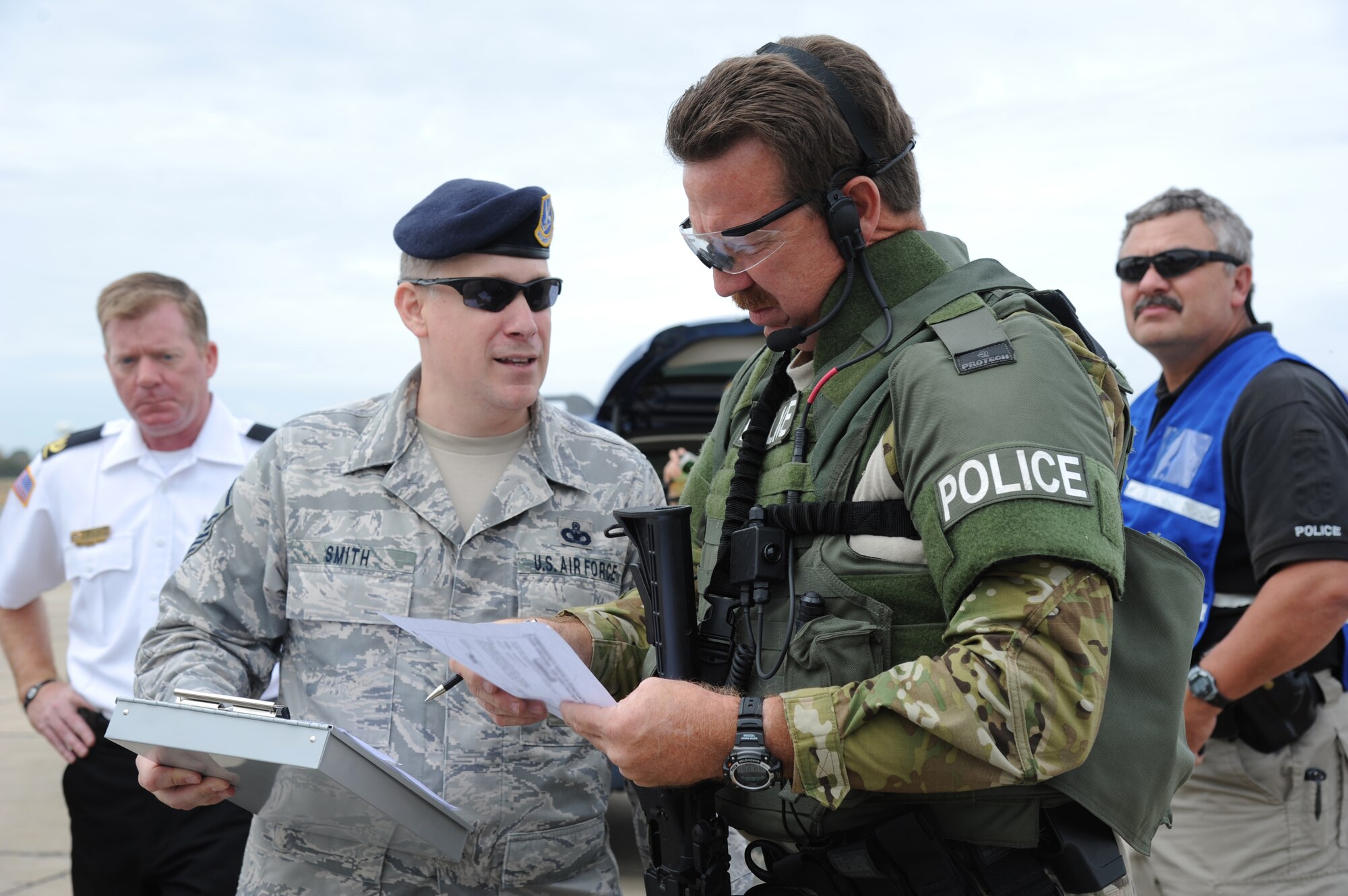 Master Sgt. Michael Smith, 81st Security Forces Squadron, and Officer Scott Doucet, the Biloxi Police Department Special Response Team commander, discuss the integration of Doucet’s officers into the base’s response to the hijacking simulation by providing an explanation of the team’s capabilities. Gary Pierson, Keesler Fire Department Deputy Fire Chief, and police Sgt. Milton Houseman, Biloxi Police Department and member of Keesler's exercise evaluation team, were standing by for further assistance during an anti-hijacking exercise on the flightline at Keesler Air Force Base, Miss., Dec. 4, 2012. The exercise scenario consisted of a disgruntled Airman, who after being denied leave during the holidays, created a fake Air Force leave form to get on a flight and hijack the aircraft to fly home.  (U.S. Air Force photo by Kemberly Groue)