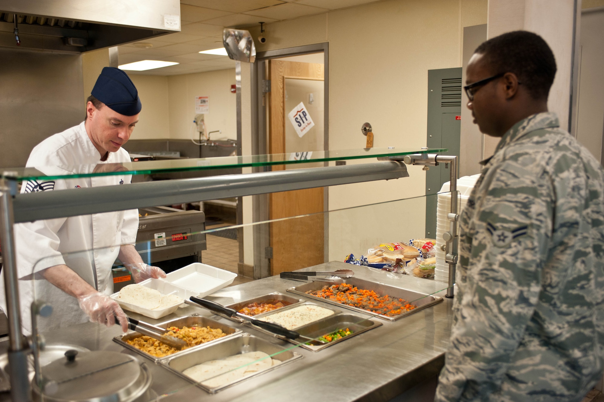 Tech. Sgt. Leigh Pears, 28th Force Support Squadron flight kitchen manager, serves an Airman food in the flight kitchen at Ellsworth Air Force Base, S.D., Dec. 4, 2012. The Air Force operates more than 270 dining facilities and flight kitchens worldwide. (U.S. Air Force photo by Airman 1st Class Zachary Hada/Released)