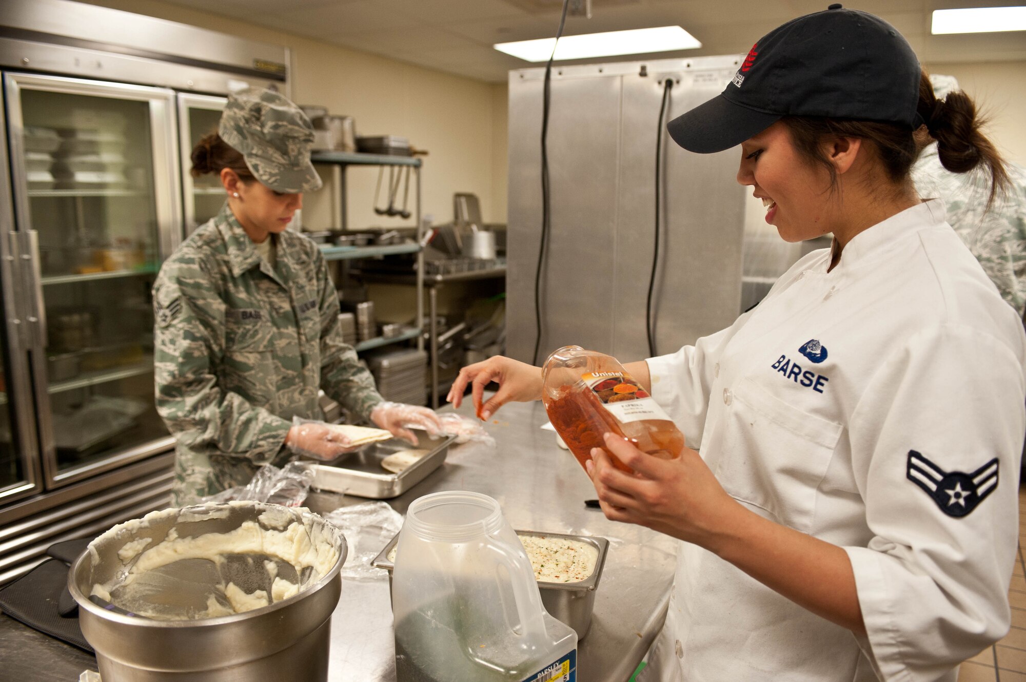 Airman 1st Class Alexandria Barse, and Senior Airman Kelsi Bass, 28th Force Support Squadron flight kitchen cooks, prepare meals for Airmen in the flight kitchen at Ellsworth Air Force Base, S.D., Dec. 4, 2012. The flight kitchen provides Ellsworth personnel with healthy and affordable meal options 24 hours a day. (U.S. Air Force photo by Airman 1st Class Zachary Hada/Released)