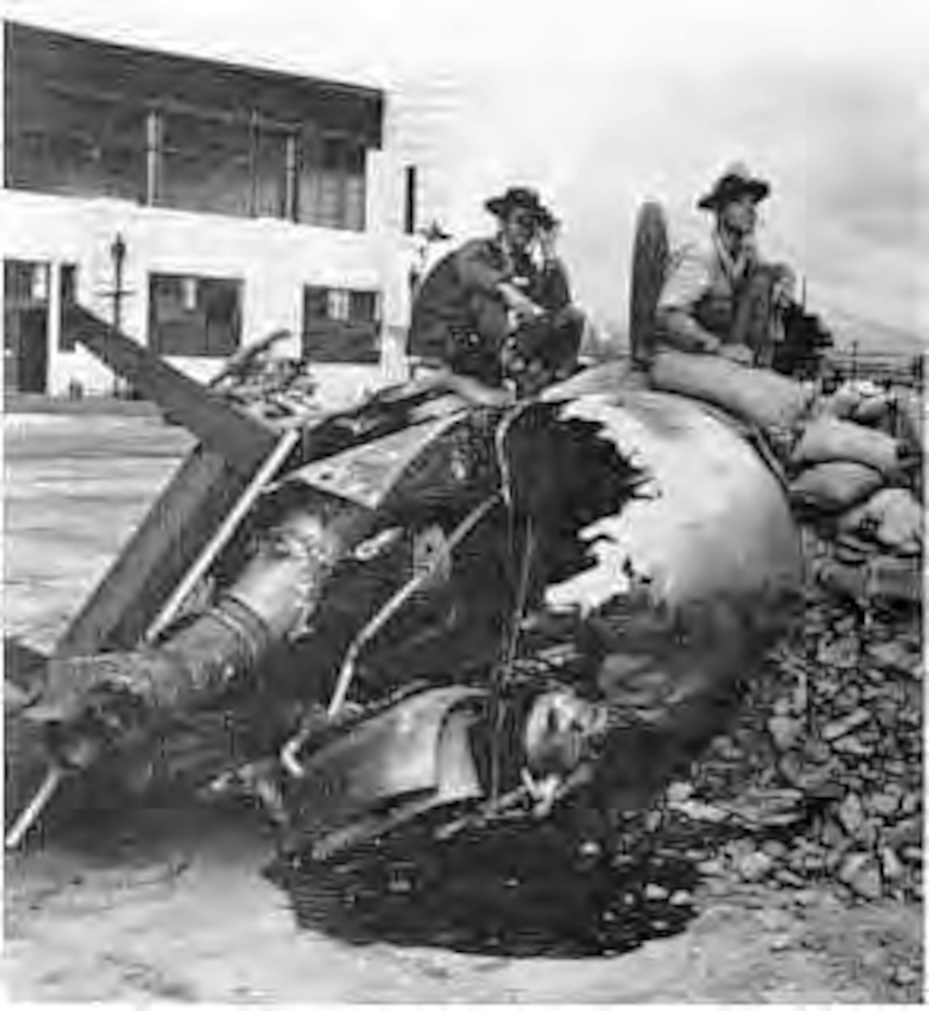 This hastily constructed gun emplacement in front of Hangar 5, Hickam Air Field, was manned shortly after the raid Dec. 7, 1941 by Pvt. 1st Class Raymond Perry (left, with binoculars) and Cpl. Howard Marquardt of South Dakota. A burned-out aircraft engine, sand bags, table, and debris from the attack made up the construction material for this bunker.   