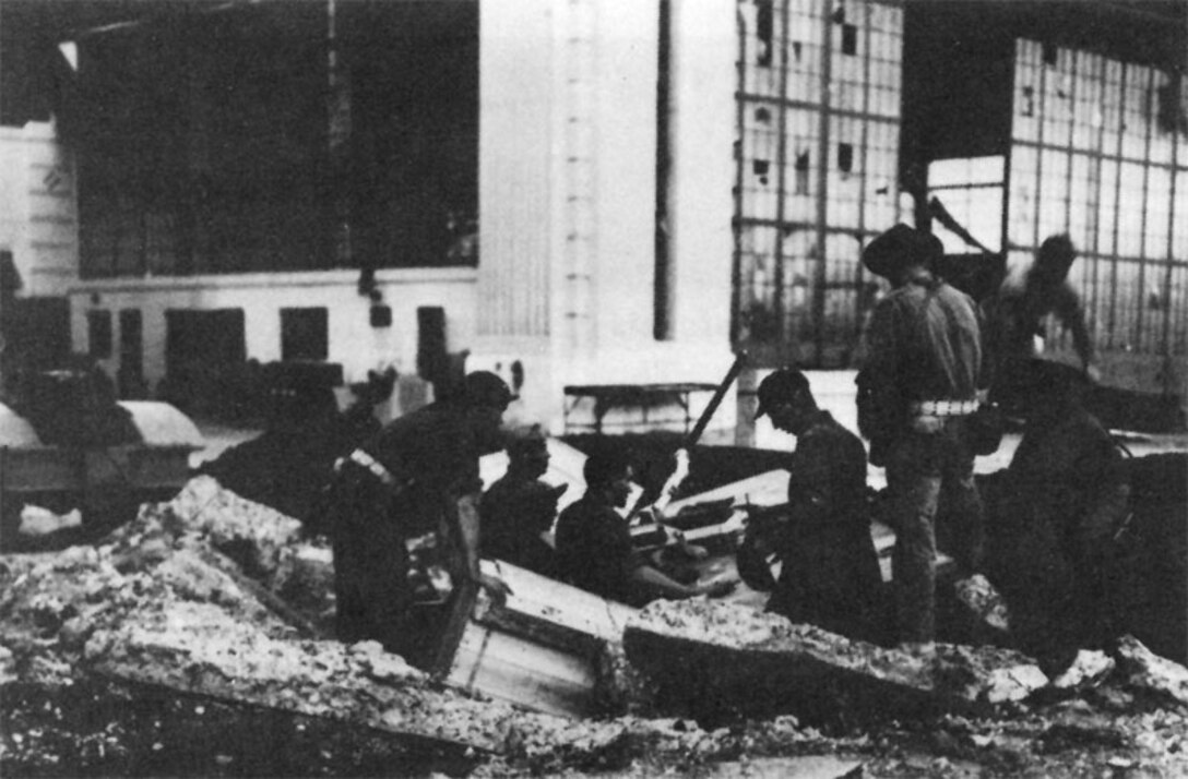 Airmen with other personnel man a gun emplacement set up in a bomb crater between Hangars 11-13 and 15-17, Hickam Field, Dec. 7, 1941.   
