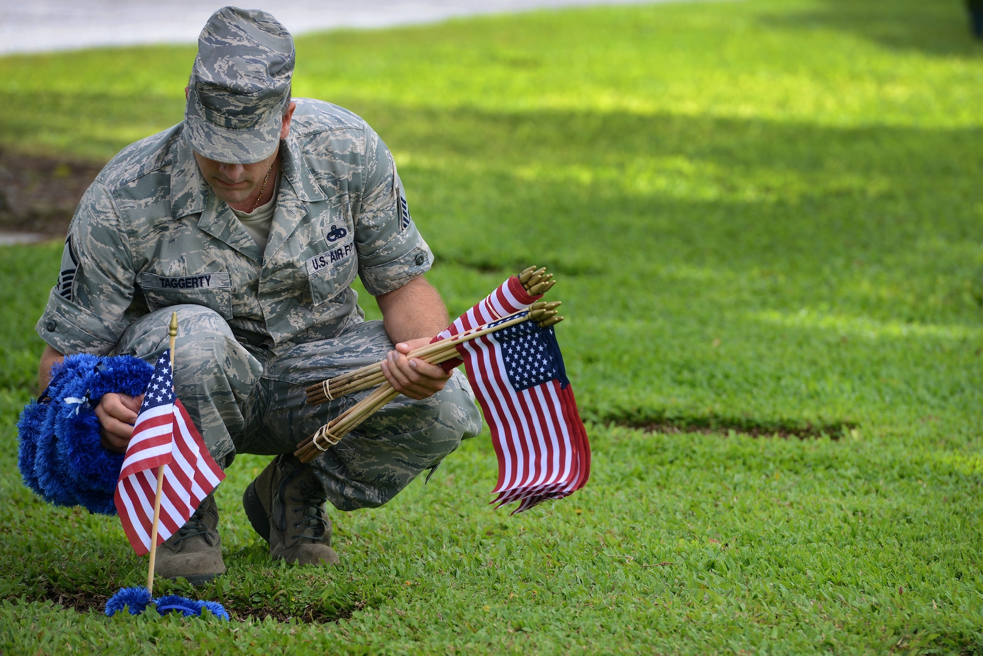 Master Sgt. Kevin Taggerty, 735th Aircraft Maintenance Squadron aircraft maintenance unit NCOIC, places a flag and a lei at the gravesite of an Army Air Forces Airman killed at Hickam Field, Dec. 7, 1941, at the National Memorial Cemetery of the Pacific at Punchbowl on Dec. 2, 2012. Ten volunteers used a roster to identify the locations at the cemetery and placed 92 flags. His daughter Ryah, 14, was part of a group of teenagers who started this project last year. (U.S. Air Force photo/Staff Sgt. Mike Meares)