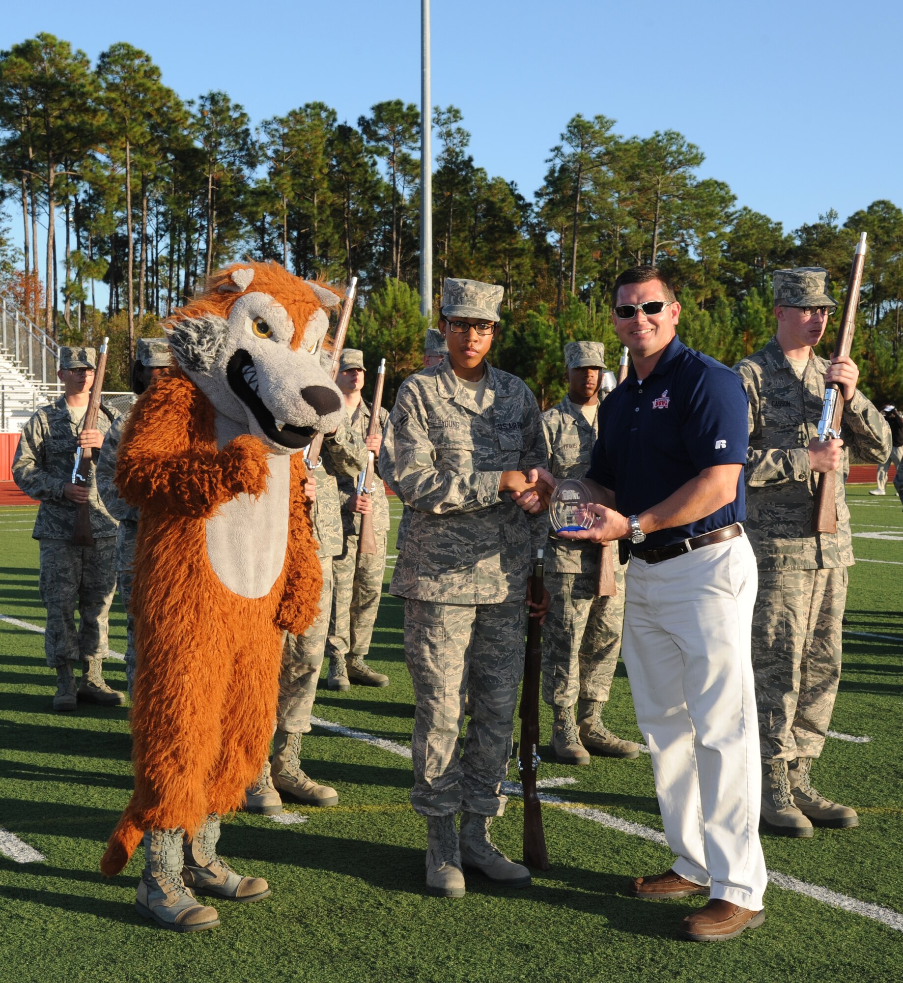 The 336th Training Squadron Red Wolf mascot and A1C Brionna Young, 336th TRS drill team member, accept the 1st place trophy from Ladd Taylor, Mississippi Bowl chairman, following a drill down competition held during half time at the 2012 Mississippi Bowl game at the Biloxi High School football stadium Dec. 2, 2012. Other participation from Keesler Air Force Base, Miss., included the 50-State Flag Team, the Honor Guard, and a C-130J Hercules fly over by the 403rd Wing.   (U.S. Air Force photo by Kemberly Groue)