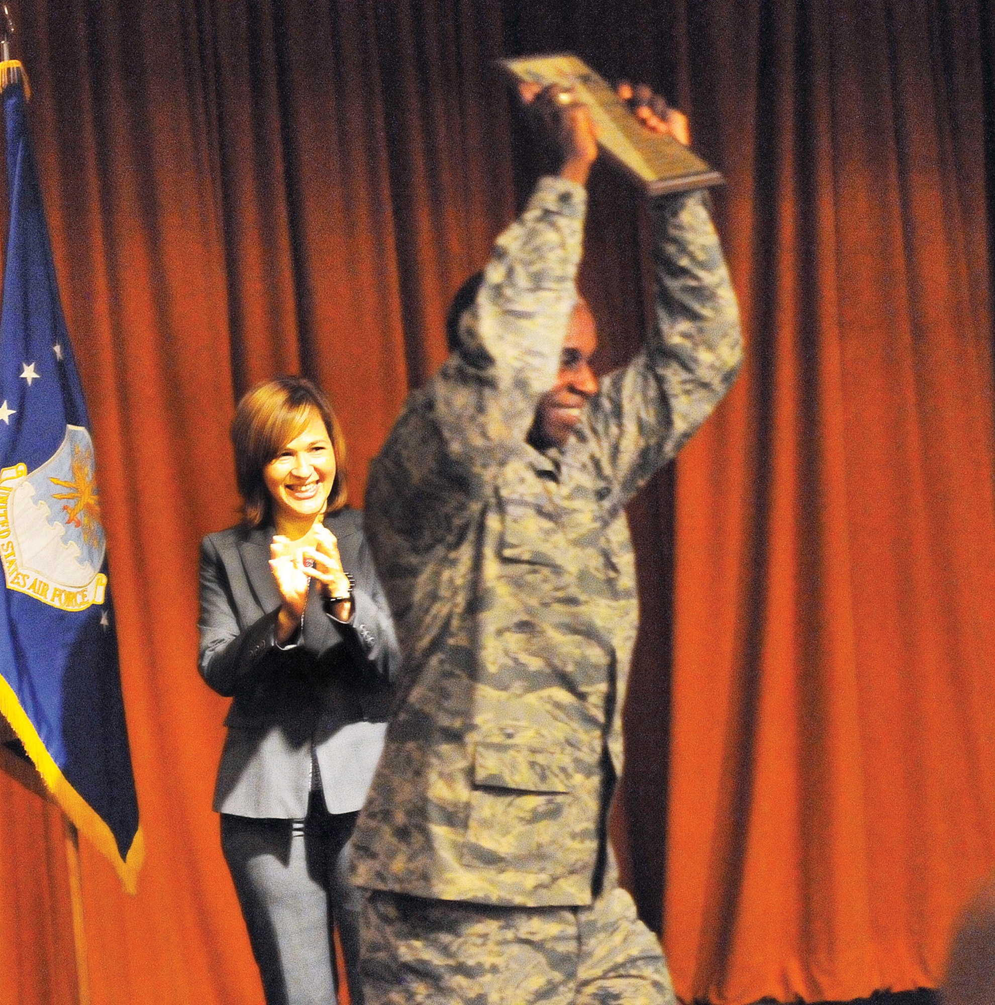 Jani Le, 2012 CFC campaign chairperson, applauds as  Brig. Gen. Cedric George, Warner Robins Air Logistics Complex commander, celebrates accepting an Early Bird recognition plaque for the command section and staff of theWR/ALC, at the victory celebration for the 2012 Combined Federal Campaign Wed.  (U. S. Air Force photo/Sue Sapp)