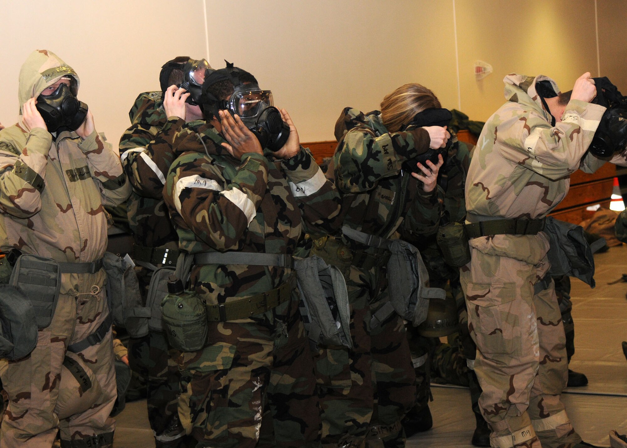 Airmen don their gas masks as they go into simulated mission-orientated protective posture level four during the Ability to Survive and Operate Rodeo Dec. 5, 2012, in the Hardstand Fitness Center at RAF Mildenhall, England. The Airmen were given two minutes to properly don their gas masks and two pairs of gloves. (U.S. Air Force photo by Airman 1st Class Kelsey Waters/Released)