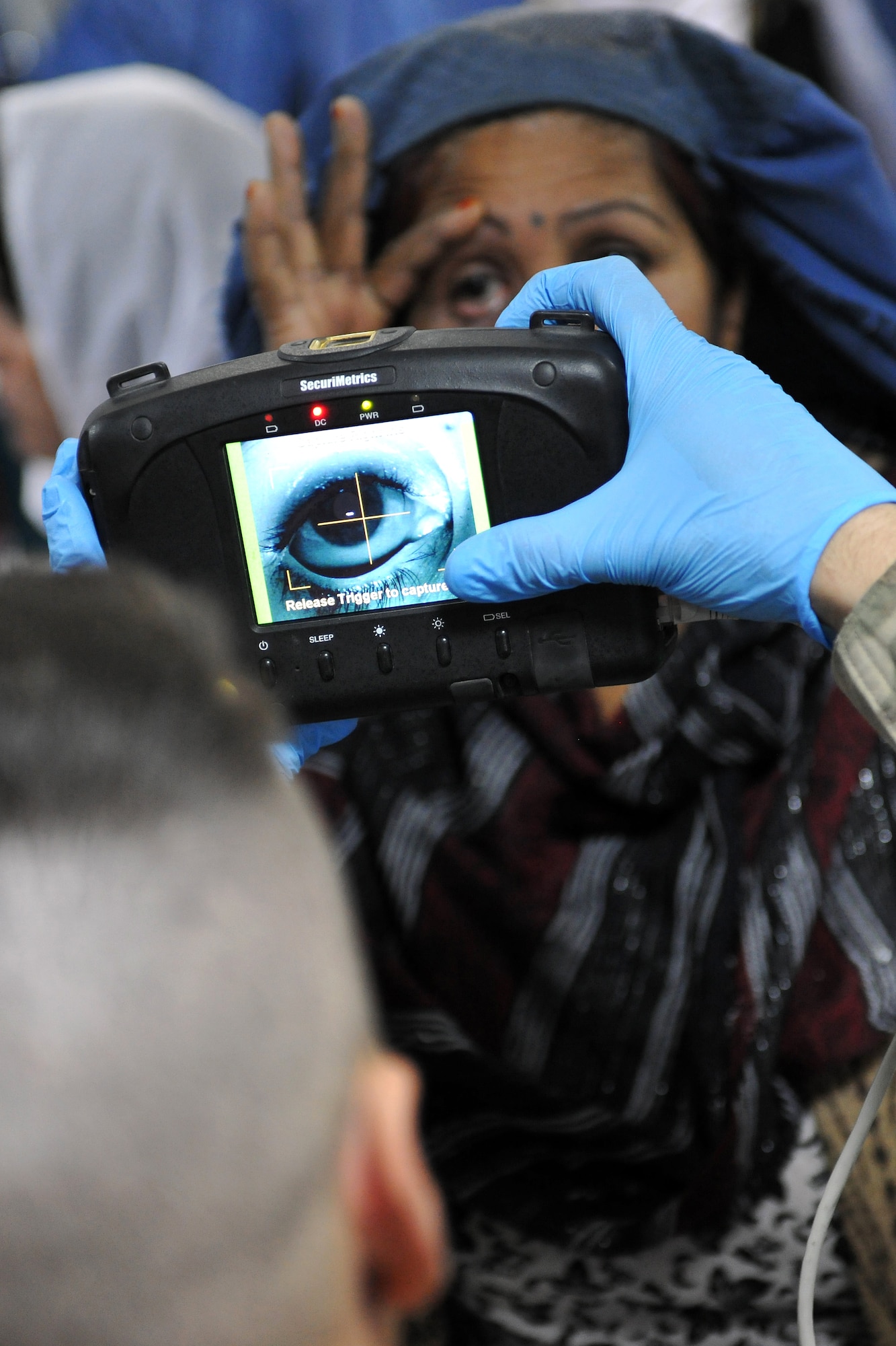 Staff Sgt. John Silvia, 455th Expeditionary Security Forces Group entry control point NCOIC, scans an Afghan woman's iris in the waiting area of the Korean Hospital at Bagram Airfield, Afghanistan, Dec. 2, 2012. Medical teams use biometrics to identify and track the records for all incoming patients by scanning their iris and fingerprints and then inputting the information into a database.  (U.S. Air Force photo/Senior Airman Chris Willis)