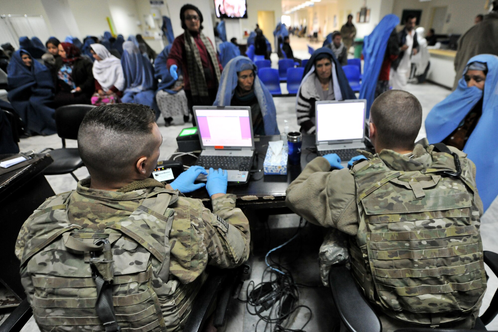 Staff Sgt. John Silvia (left) and Senior Airman Bradley Rae, both from the 455th Expeditionary Security Forces Group bravo sector, collect biometric information from local Afghans receiving medical services at Bagram Airfield, Afghanistan, Dec. 2, 2012 Medical teams use biometrics to identify and track the records for all incoming patients by scanning their iris and fingerprints and then inputting the information into a database.  (U.S. Air Force photo/Senior Airman Chris Willis)
