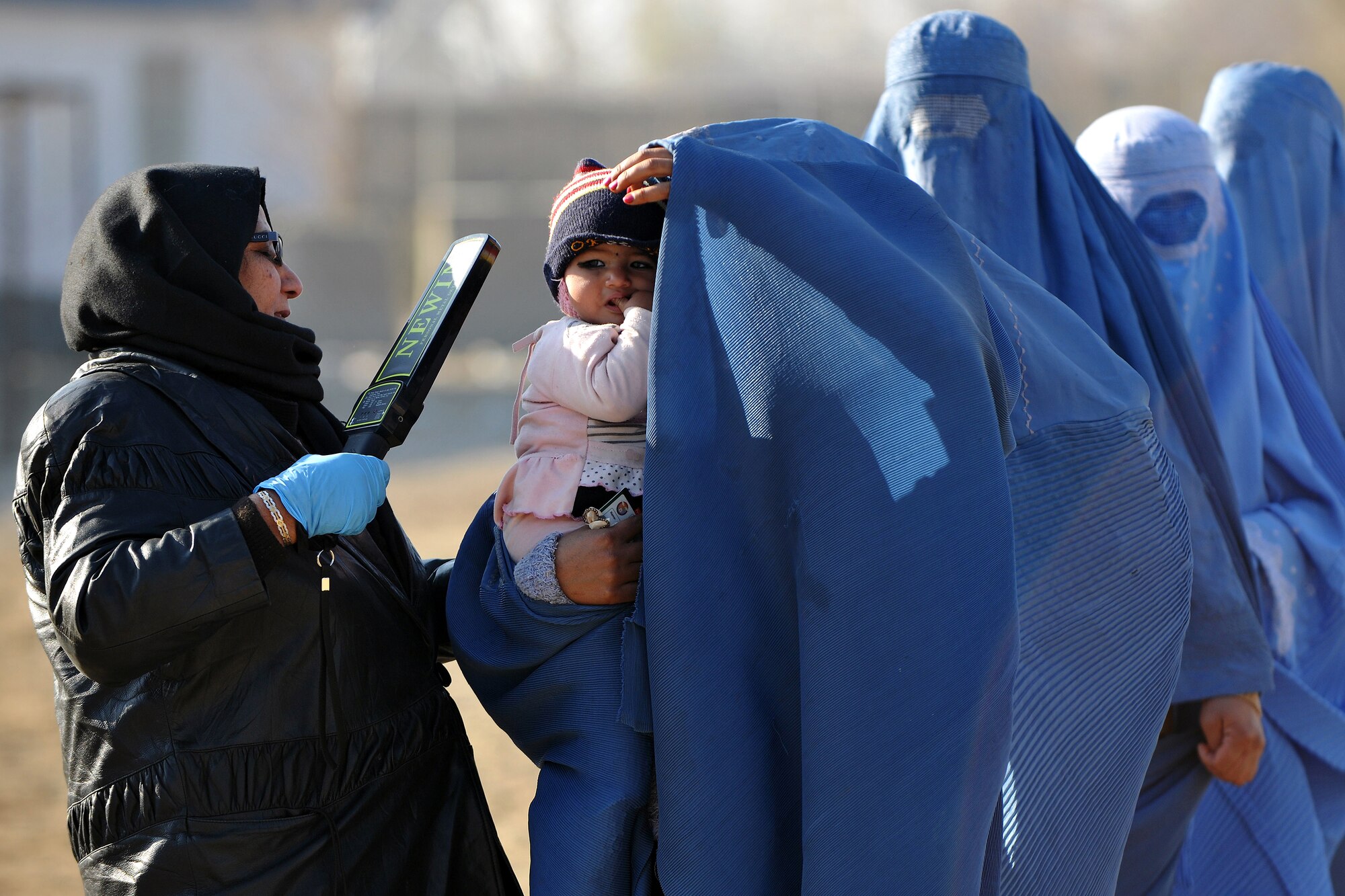 A female Afghan guard processes local women through the medical entry control point at Bagram Airfield, Afghanistan, Dec. 2, 2012.  Members of the 455th Expeditionary Security Forces Group bravo sector and Afghan local guards process as many as 400 people from outside the gate needing services ranging from basic clinical care to student vocational programs.  (U.S. Air Force photo/Senior Airman Chris Willis)