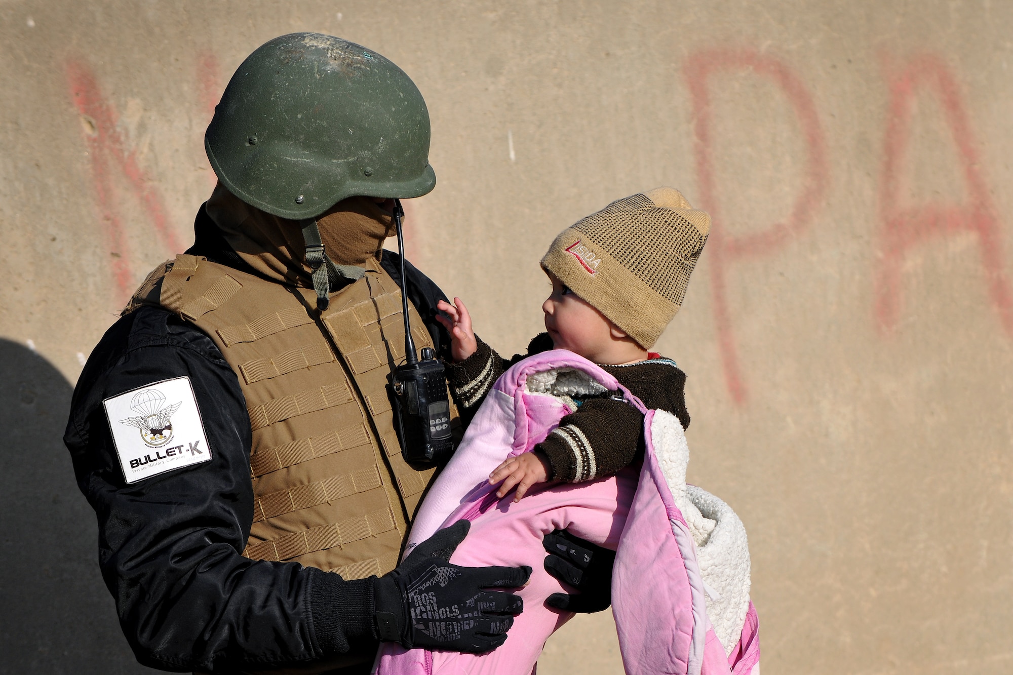An Afghan guard holds a local baby while her mother processes through the medical entry control point at Bagram Airfield, Afghanistan, Dec. 2, 2012.  Members of the 455th Expeditionary Security Forces Group bravo sector and Afghan local guards process as many as 400 people from outside the gate needing services ranging from basic clinical care to student vocational programs.  (U.S. Air Force photo/Senior Airman Chris Willis)