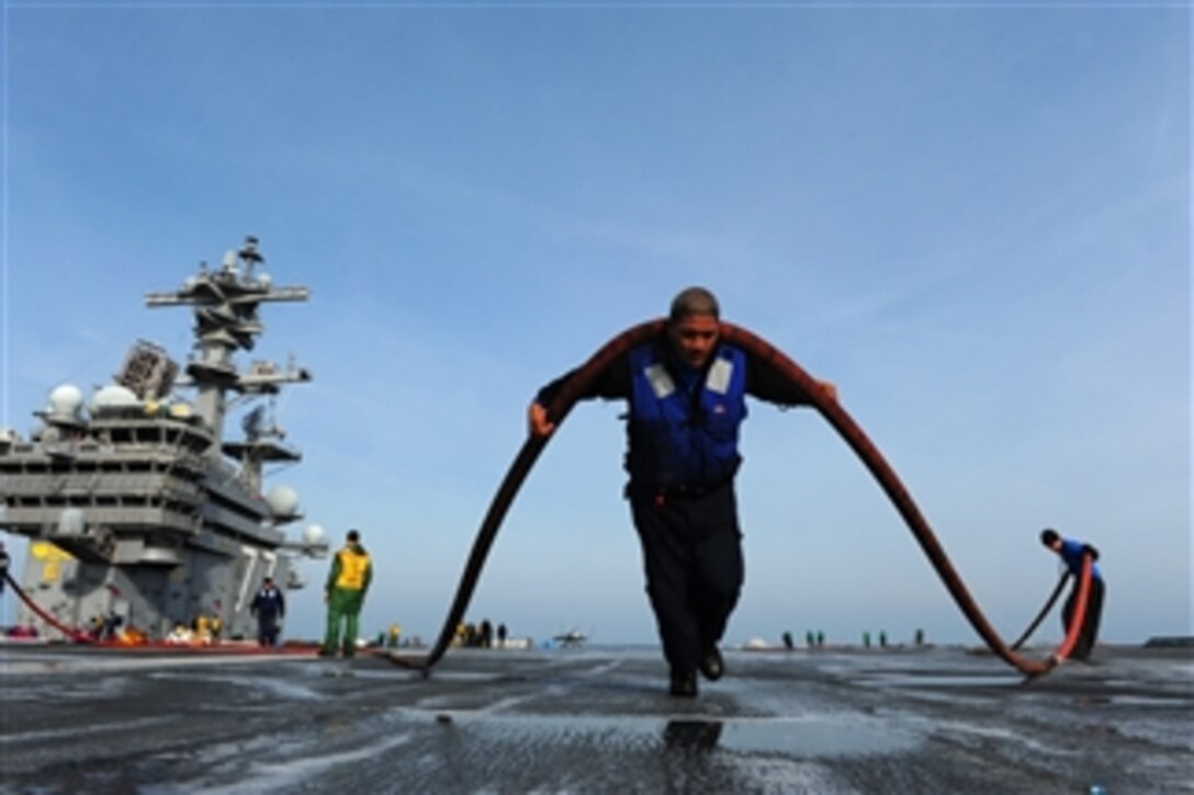 Airman David Saili moves a hose across the flight deck of the aircraft carrier USS George H.W. Bush (CVN 77) as the ship operates in the Atlantic Ocean on Dec. 2, 2012.  Bush is conducting sea trials in collaboration with Norfolk Naval Shipyard to train crewmembers and ensure operability of equipment and systems.  