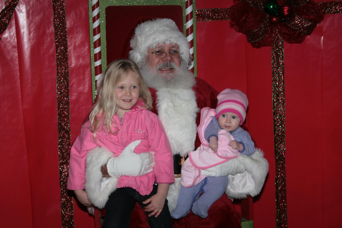 Riley Darnell, 3, and her 4-month-old sister, Jaidyn, the daughters of Cpl. Partrick Darnell of Marine Light Attack Helicopter Squadron 467, sit on Santa’s lap after telling him what they want for Christmas at the annual Christmas tree lighting in front of the Marine Corps Exchange here Nov. 30. Children and their families lined up for a chance to sit on Santa’s lap, and to get a gift from him.   