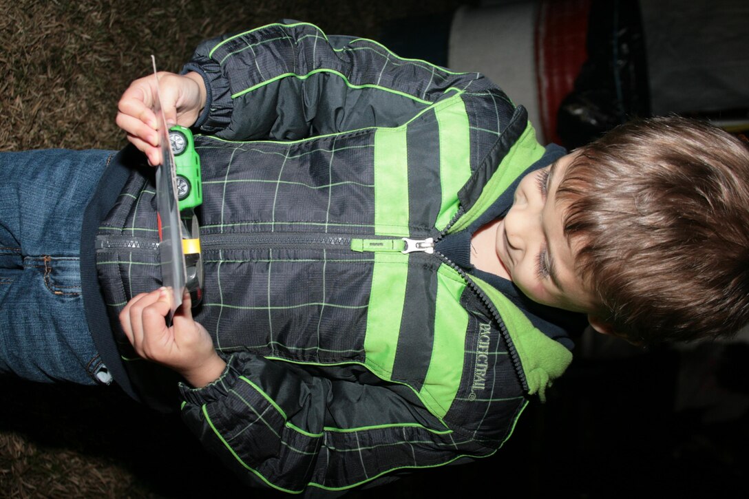 Nikolai, the 3-year-old son of Capt. Eddie Cardona of Marine Unmanned Aerial Vehicle Squadron 1, admires the gift Santa Claus gave him at the air station's annual Christmas tree lighting in front of the Marine Corps Exchange Nov. 30.