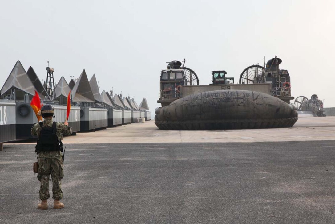 A sailor assigned to the USS Rushmore guides a Landing Craft Air Cushion to load Marines and cargo from the 15th Marine Expeditionary Unit  to transport them from Camp Patriot, Kuwait, to the USS Rushmore on Nov. 29. The Marines recently completed Eager Mace 13, a routine training exercise that focused on promoting regional security, stability and mutual interests in the region. The 15th MEU is deployed as part of the Peleliu Amphibious Ready Group as a U.S. Central Command theater reserve force, providing support for maritime security operations and theater security cooperation efforts in the U.S. 5th Fleet area of responsibility. (U.S. Marine Corps photo by Cpl. Timothy R. Childers)