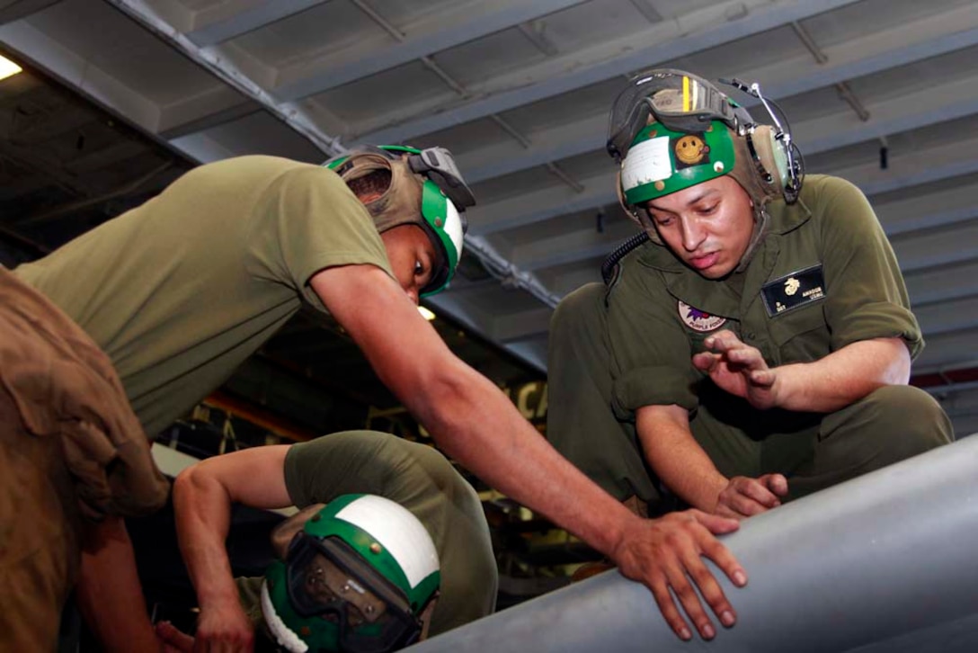 Sergeant Daniel Amador (right), and Lance Cpl. Marley C. Wilkerson, both avionics technicians with Marine Medium Helicopter Squadron 364 (Rein.), 15th Marine Expeditionary Unit, perform maintenance on an AV-8B Harrier in the hangar bay of the USS Peleliu, Nov. 29. The 15th MEU is deployed as part of the Peleliu Amphibious Ready Group as a U.S. Central Command theater reserve force, providing support for maritime security operations and theater security cooperation efforts in the U.S. 5th Fleet area of responsibility. Amador is from El Paso, Texas, and Wilkerson, 20, is from Gary, Ind. (U.S. Marine Corps photo by Cpl. John Robbart III/Released)