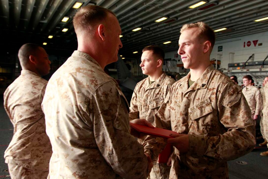 Newly promoted Cpl. Derrick T. Nelson, scout observer, Command Element, 15th Marine Expeditionary Unit, receives his promotion warrant from his commanding officer, Col. Scott D. Campbell, during the Command Element's promotion and awards ceremony in the hangar bay of the USS Peleliu, Dec. 1. The 15th MEU is deployed as part of the Peleliu Amphibious Ready Group as a U.S. Central Command theater reserve force, providing support for maritime security operations and theater security cooperation efforts in the U.S. 5th Fleet area of responsibility. Nelson, 20, is from Huntington Beach, Calif. (U.S. Marine Corps photo by Cpl. John Robbart III/Released)