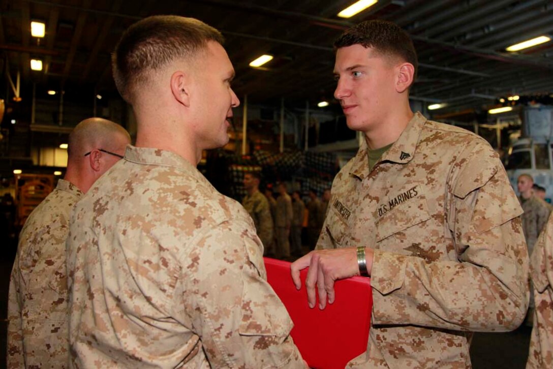 Newly promoted Cpl. Aaron M. Lantznester, team leader, Kilo Company, Battalion Landing Team 3/5, 15th Marine Expeditionary Unit, receives his promotion warrant from his commanding officer, Capt. James E. Dee, during Kilo Companyâ€™s promotion ceremony in the hangar bay of the USS Peleliu, Dec. 1. The 15th MEU is deployed as part of the Peleliu Amphibious Ready Group as a U.S. Central Command theater reserve force, providing support for maritime security operations and theater security cooperation efforts in the U.S. 5th Fleet area of responsibility. Lantznester, 22, is from Grand Rapids, Mich. (U.S. Marine Corps photo by Cpl. John Robbart III/Released)