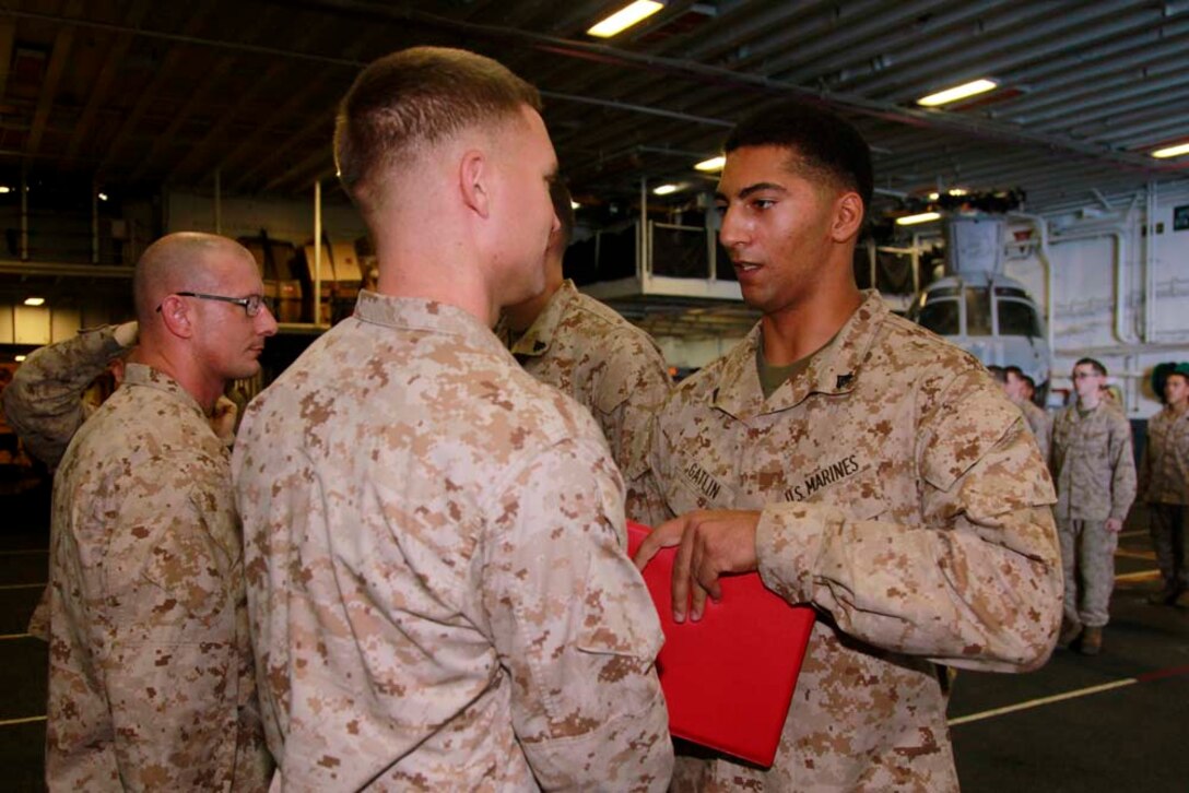 Newly promoted Cpl. Andre R. Gatlin, team leader, Kilo Company, Battalion Landing Team 3/5, 15th Marine Expeditionary Unit, receives his promotion warrant from his commanding officer, Capt. James E. Dee, during Kilo Company's promotion ceremony in the hangar bay of the USS Peleliu, Dec. 1. The 15th MEU is deployed as part of the Peleliu Amphibious Ready Group as a U.S. Central Command theater reserve force, providing support for maritime security operations and theater security cooperation efforts in the U.S. 5th Fleet area of responsibility. Gatlin, 26, is from San Diego. (U.S. Marine Corps photo by Cpl. John Robbart III/Released)