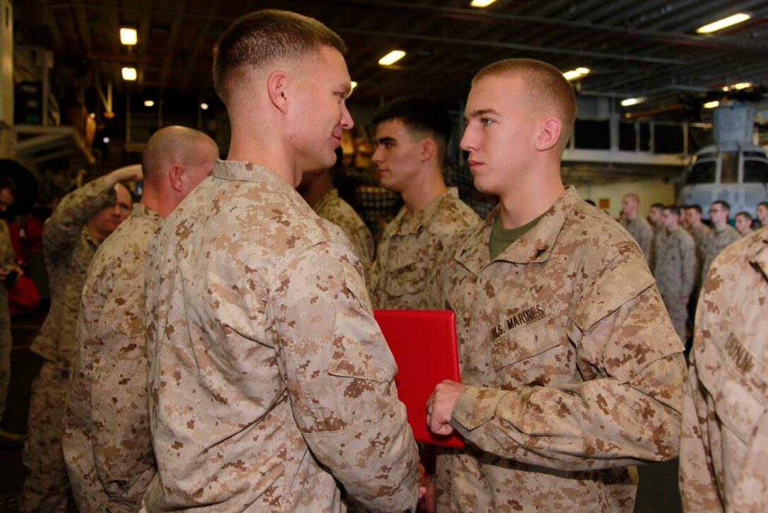 Newly promoted Lance Cpl. Daniel L. Gordon, assaultman, Kilo Company, Battalion Landing Team 3/5, 15th Marine Expeditionary Unit, receives his promotion warrant from his commanding officer, Capt. James E. Dee, during Kilo Companyâ€™s promotion ceremony in the hangar bay of the USS Peleliu, Dec. 1. The 15th MEU is deployed as part of the Peleliu Amphibious Ready Group as a U.S. Central Command theater reserve force, providing support for maritime security operations and theater security cooperation efforts in the U.S. 5th Fleet area of responsibility. Gordon is from Stephenville, Texas. (U.S. Marine Corps photo by Cpl. John Robbart III/Released)