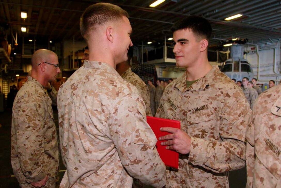 Newly promoted Cpl. Ryan A. Echelbarger, squad leader, Kilo Company, Battalion Landing Team 3/5, 15th Marine Expeditionary Unit, receives his promotion warrant from his commanding officer, Capt. James E. Dee, during Kilo Company's promotion ceremony in the hangar bay of the USS Peleliu, Dec. 1. The 15th MEU is deployed as part of the Peleliu Amphibious Ready Group as a U.S. Central Command theater reserve force, providing support for maritime security operations and theater security cooperation efforts in the U.S. 5th Fleet area of responsibility. Echelbarger, 21, is from Columbus, Ohio. (U.S. Marine Corps photo by Cpl. John Robbart III/Released)