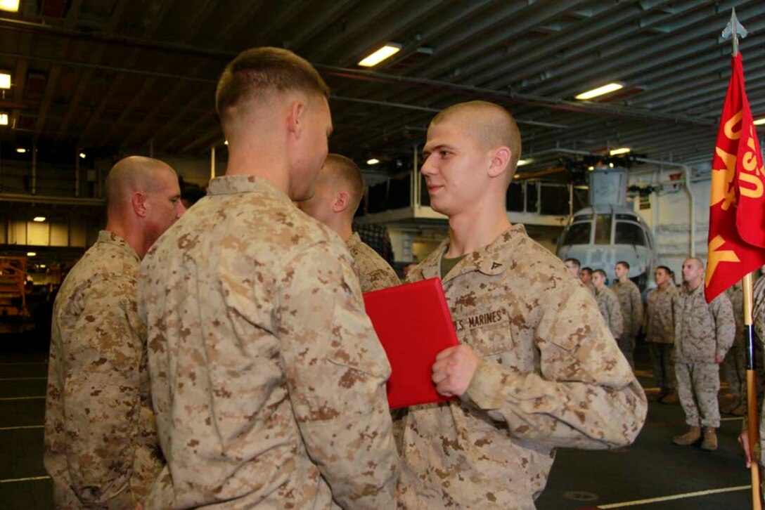 Newly promoted Lance Cpl. Clayton A. Dunn, machine gunner, Kilo Company, Battalion Landing Team 3/5, 15th Marine Expeditionary Unit, receives his promotion warrant from his commanding officer, Capt. James E. Dee, during Kilo Company's promotion ceremony in the hangar bay of the USS Peleliu, Dec. 1. The 15th MEU is deployed as part of the Peleliu Amphibious Ready Group as a U.S. Central Command theater reserve force, providing support for maritime security operations and theater security cooperation efforts in the U.S. 5th Fleet area of responsibility. (U.S. Marine Corps photo by Cpl. John Robbart III/Released)