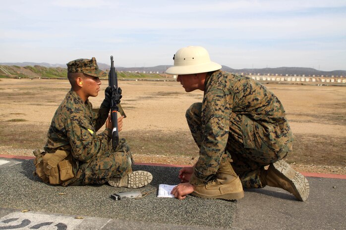 A recruit of Company H, 2nd Recruit Training Battalion, listens as his range coach reviews his shots and advises him at Edson Range aboard Marine Corps Base Camp Pendleton, Calif. Nov. 27.  Recruits learn and apply shooting fundamentals during grass week and firing week.  They will qualify on the last day of firing week.
