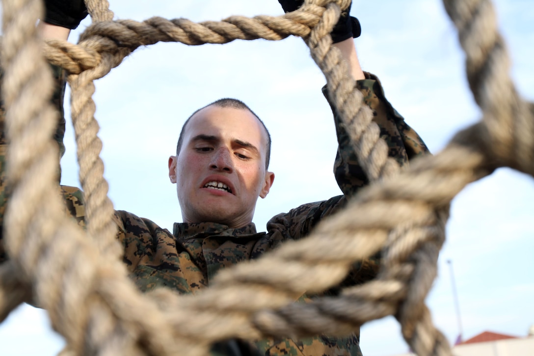 A Recruit of Company A, 1st Recruit Training Battalion, climbs his way over an obstacle aboard Marine Corps Recruit Depot San Diego, Nov. 29. The recruits were required to climb up and over the approximately 10 foot cargo net climb during a confidence course.