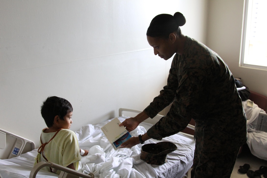 Cpl. Tasia Wise reads a book with a child at the pediatric center in Guam Memorial Hospital Dec. 6, during Exercise Forager Fury 2012.  Wise and 10 other service members volunteered their time to help clean windows at the hospital and had the pleasure of meeting children in the pediatric center. Wise is an Aviation Maintenance Administration Clerk with Marine All Weather Fighter Attack Squadron 224 which is under Unit Deployment Program with Marine Aircraft Group 12, 1st Marine Aircraft Wing, III Marine Expeditionary Force.
