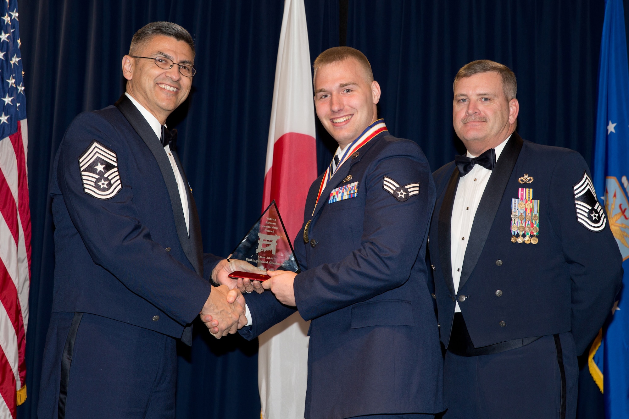 YOKOTA AIR BASE, Japan -- Senior Airman, Phillip Hageberg (center), 730th Air Mobility Suqadron, is awarded the Distinguished Graduate Award during the Airman Leadership School Class 13-A graduation ceremony at Yokota Air Base, Japan, Dec. 6, 2012. Command Chief Master Sgt. Manuel Roblesreynoso (left), 374th Airlift Wing, and Chief Master Sgt. Eric Honeycutt, 374th Civil Engineer Squadron, representatives of the Civil Engineer Association, presented the award to Hageberg during the ceremony. (U.S. Air Force photo by Osakabe Yasuo) 