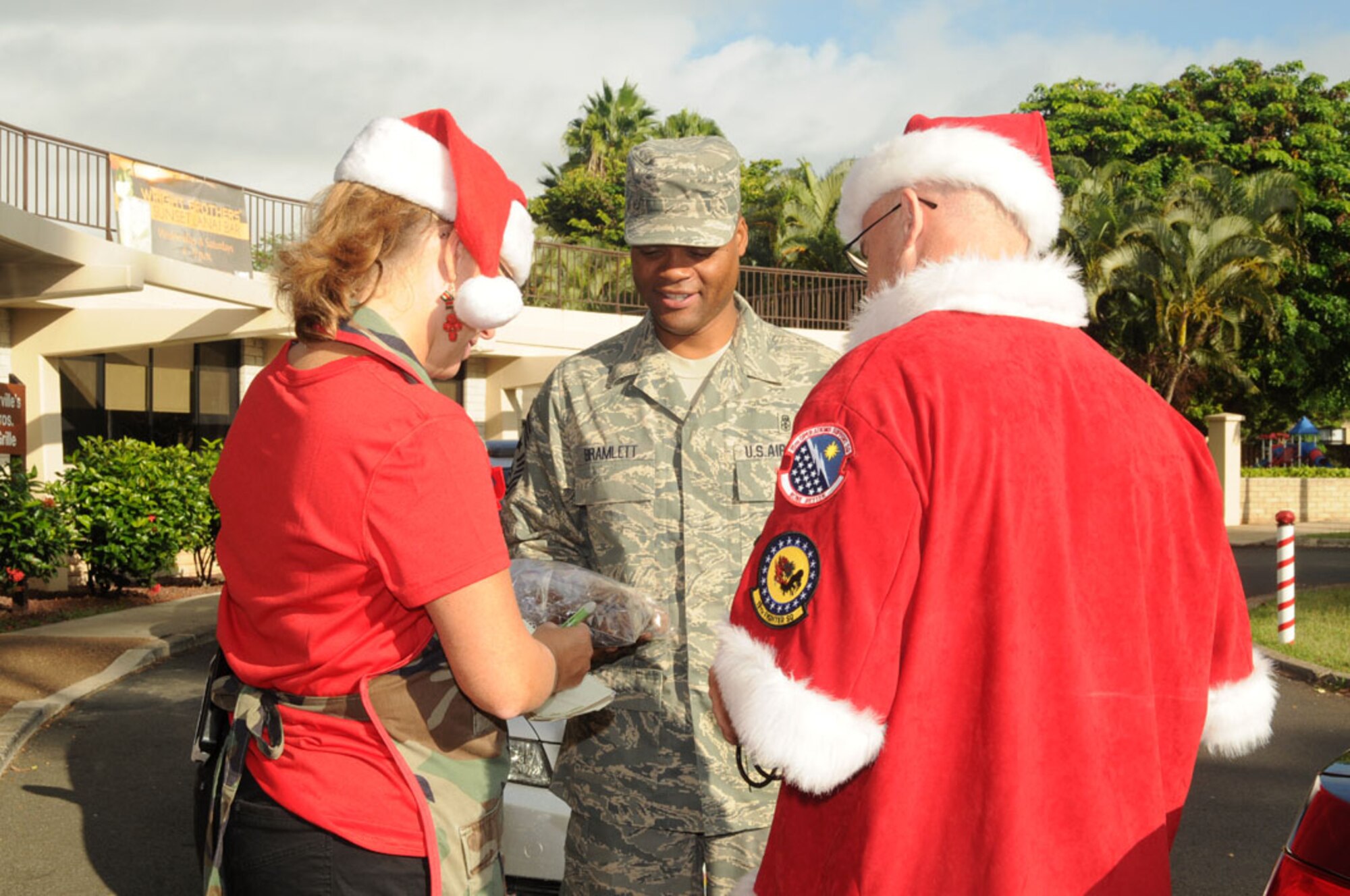 Chief Master Sgt. Leslie Bramlett, Command Chief, 15th Wing,
delivers cookies to Angela Bennett, military spouse, and Chief Master Sgt.
Michael Morris, 15th Operations Group near the Wright Brother's Cafe on
Joint Base Pearl Harbor-Hickam, Hawaii, 4 Dec 2012. The 15th Wing Cookie
Caper is hosted by the 15th Operations Group, and cookie donations are being
collected to send to deployed Airmen this holiday season.  Photo by David D.
Underwood, Jr.

